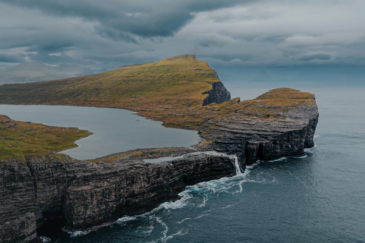 Sheer cliffs meeting the ocean under a stormy sky
