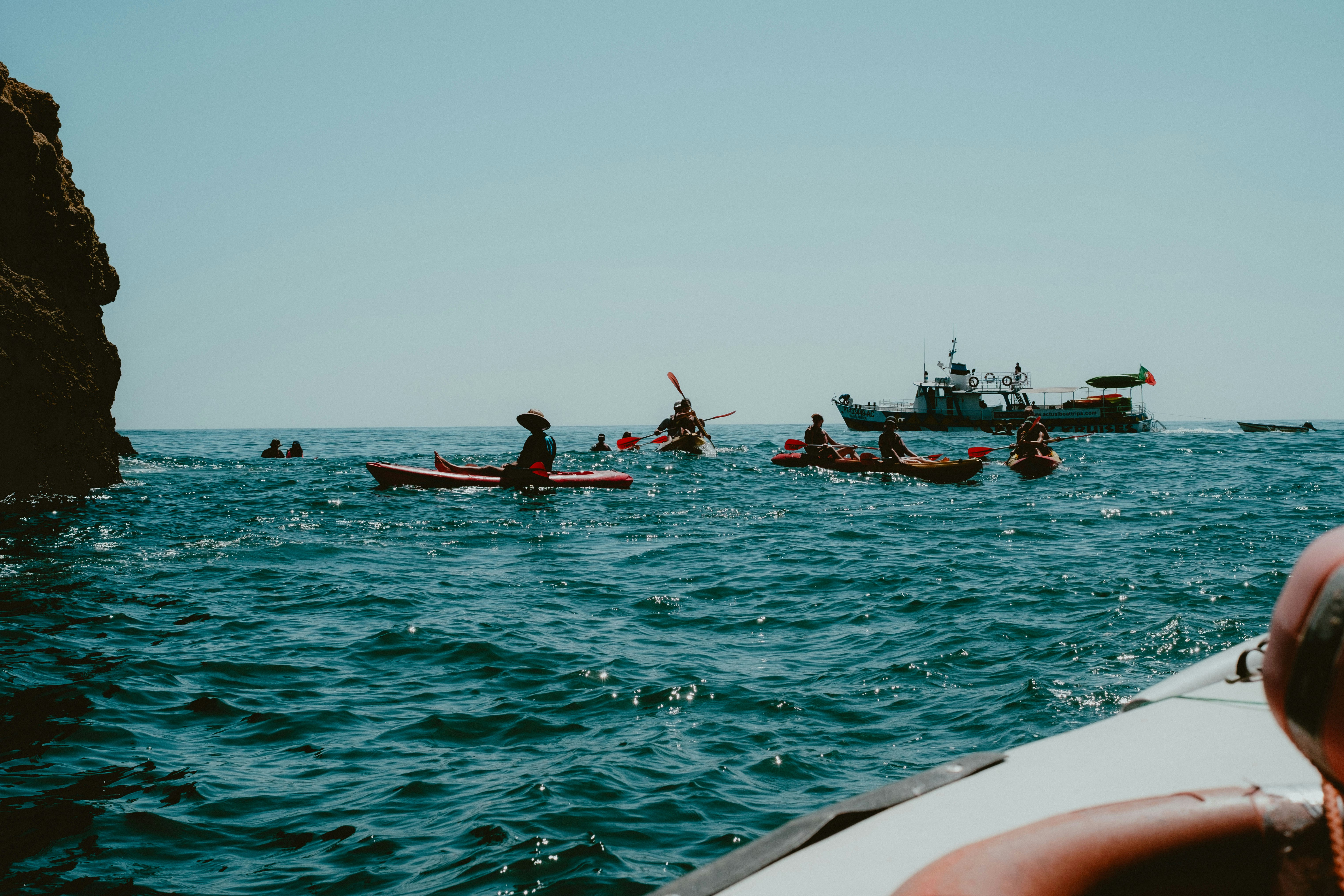 Kayakers paddle on the ocean near a boat