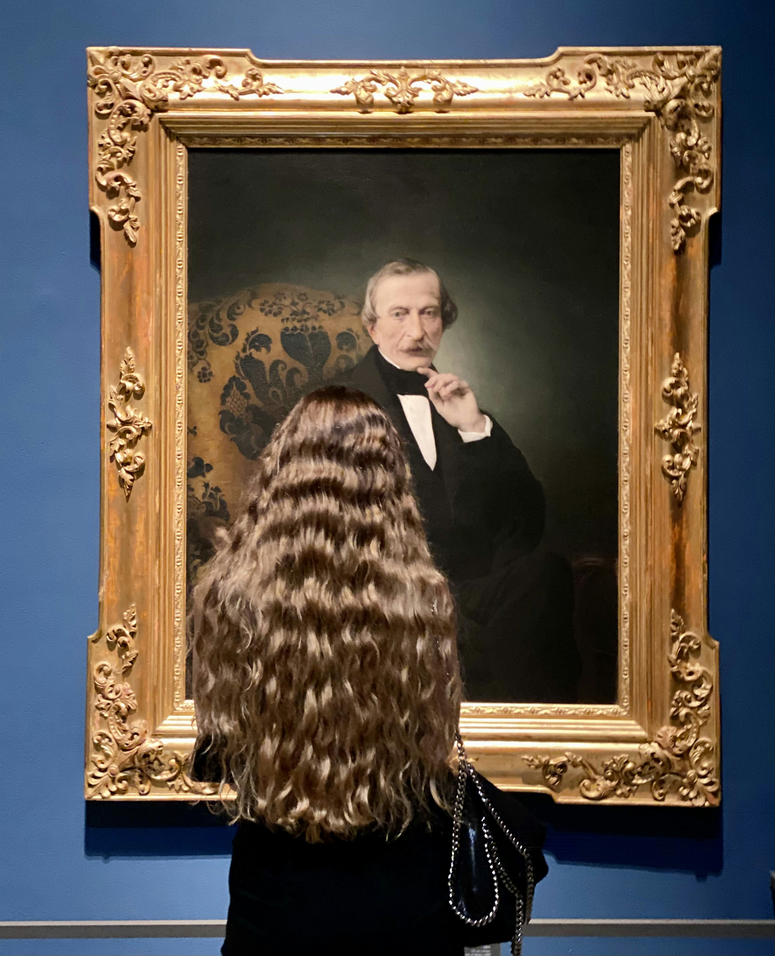 Woman looks at a framed portrait of a man.