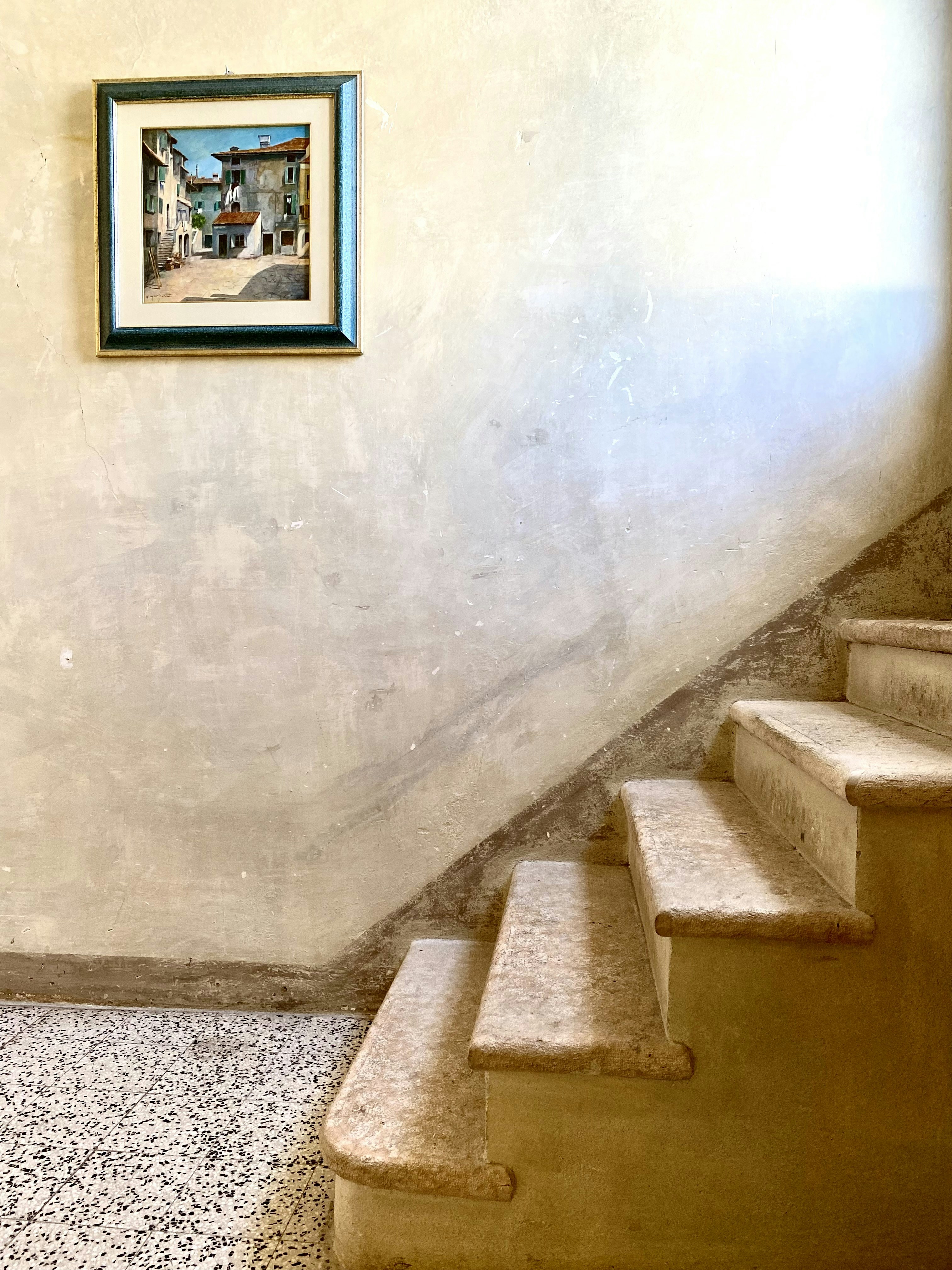 Framed painting hangs above stone staircase