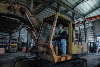Man sits in an old excavator in a workshop.