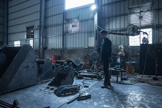Man standing in a cluttered workshop with machinery.