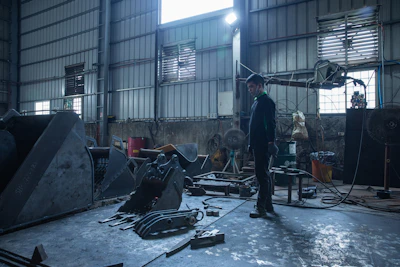 Man standing in a cluttered workshop with machinery.