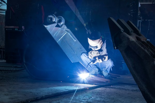 Soldador trabajando en planta industrial, terreno del posicionamiento web para distribuidores de equipo de soldadura industrial