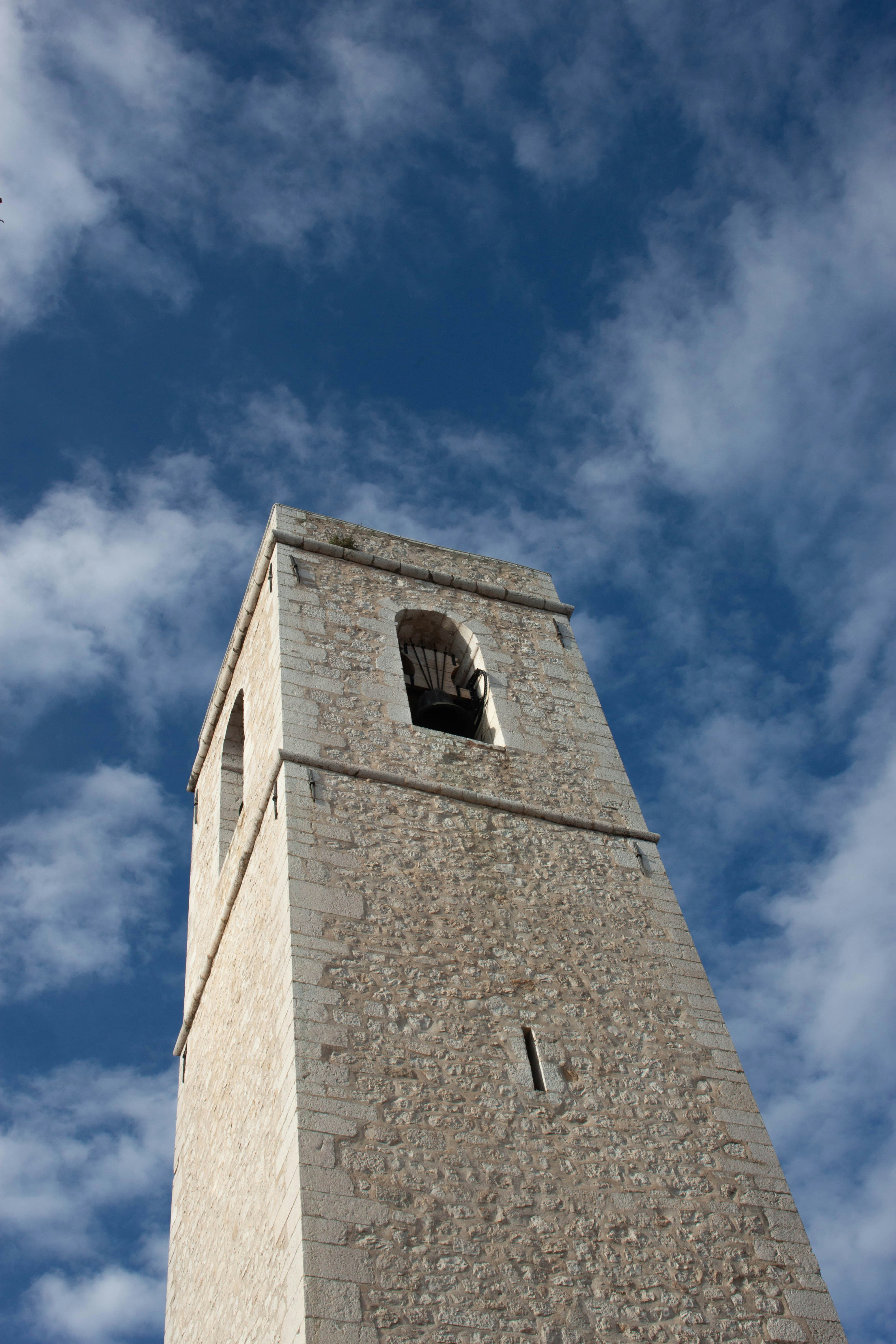Un campanario de piedra contra un cielo azul nublado