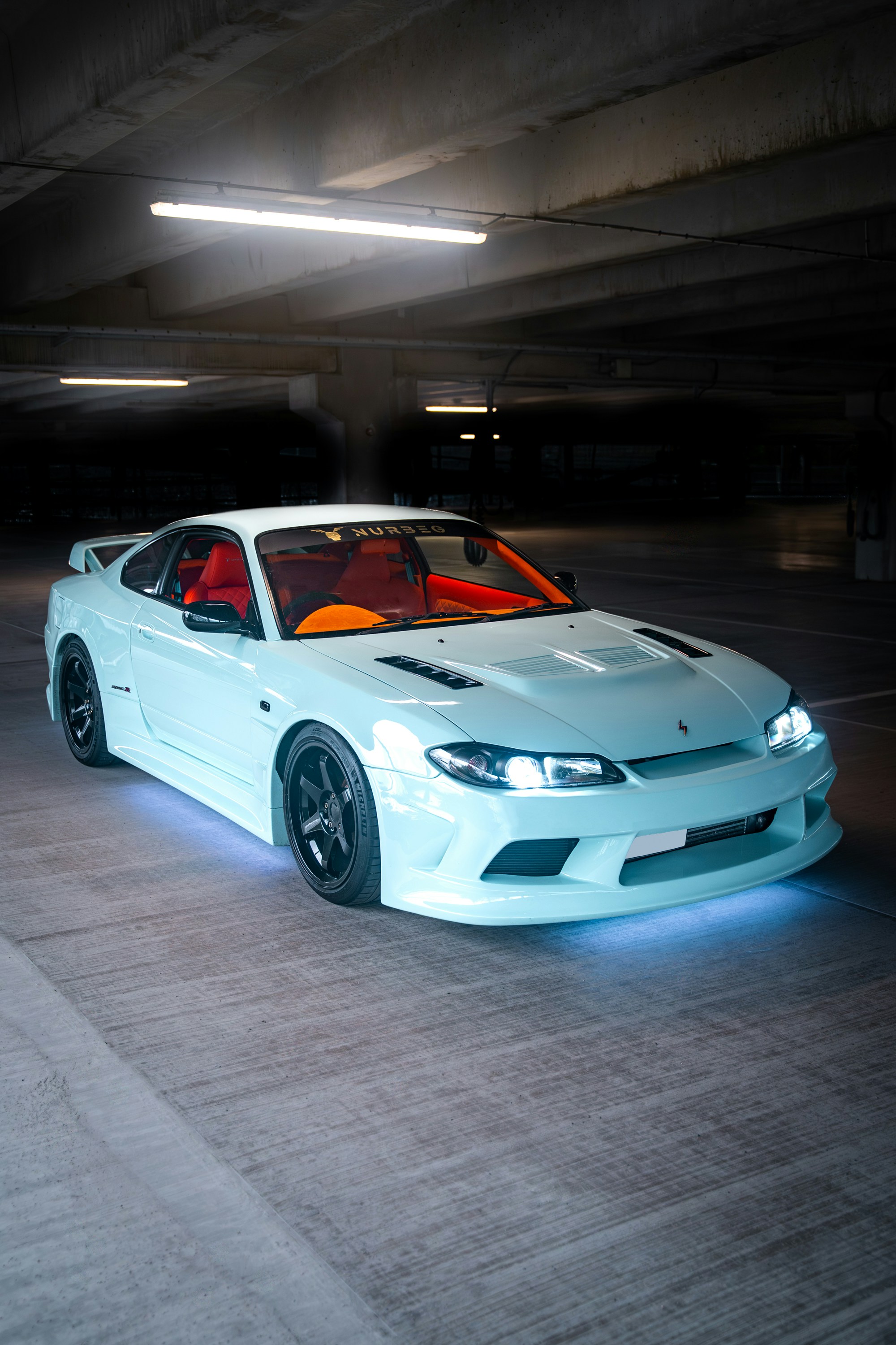 Hellblauer Sportwagen mit orangefarbenem Interieur in der Garage