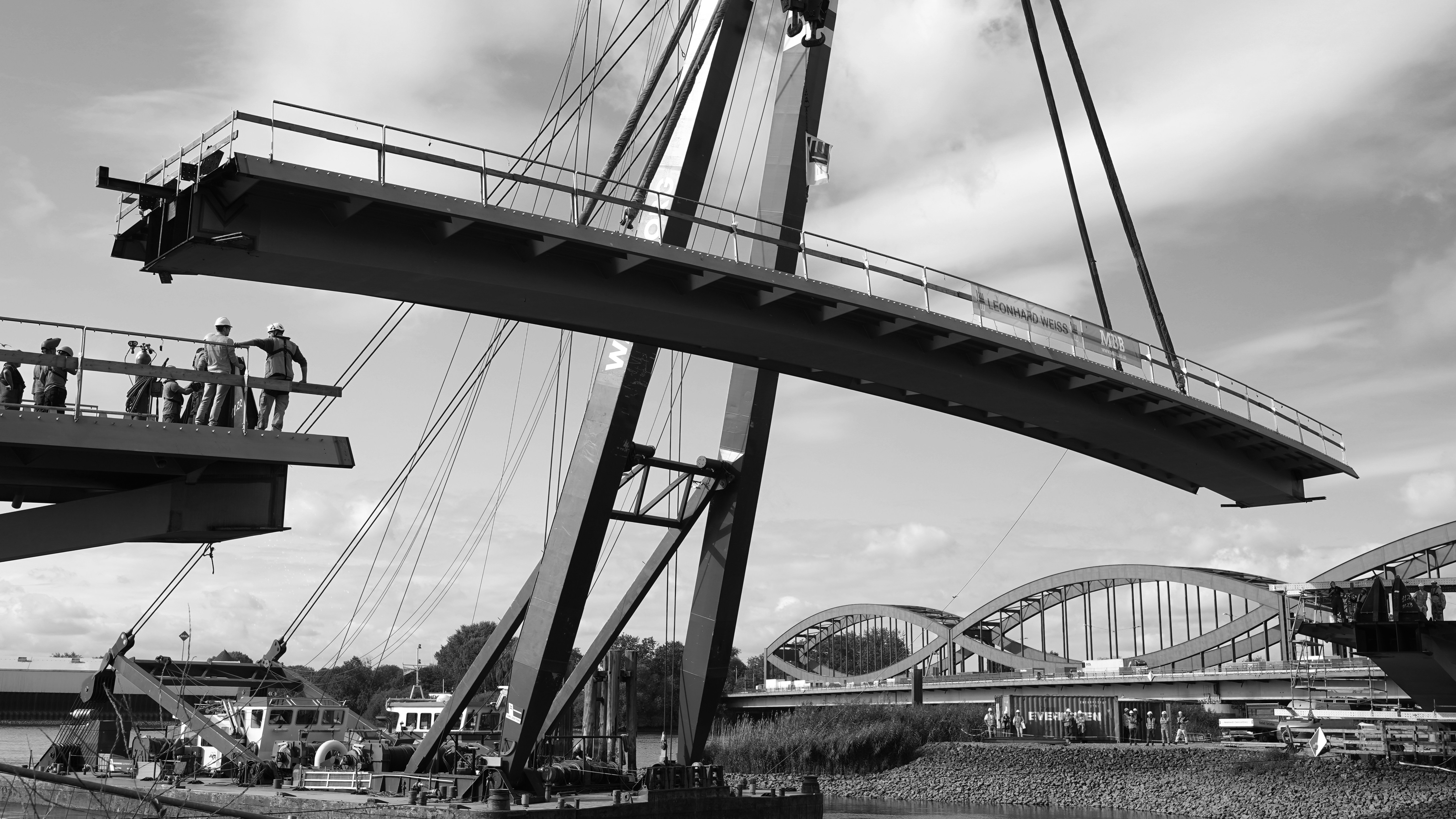 Workers lifting large bridge section with crane