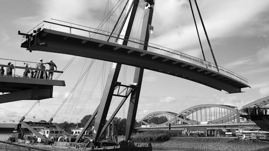 Workers lifting a large bridge section with crane