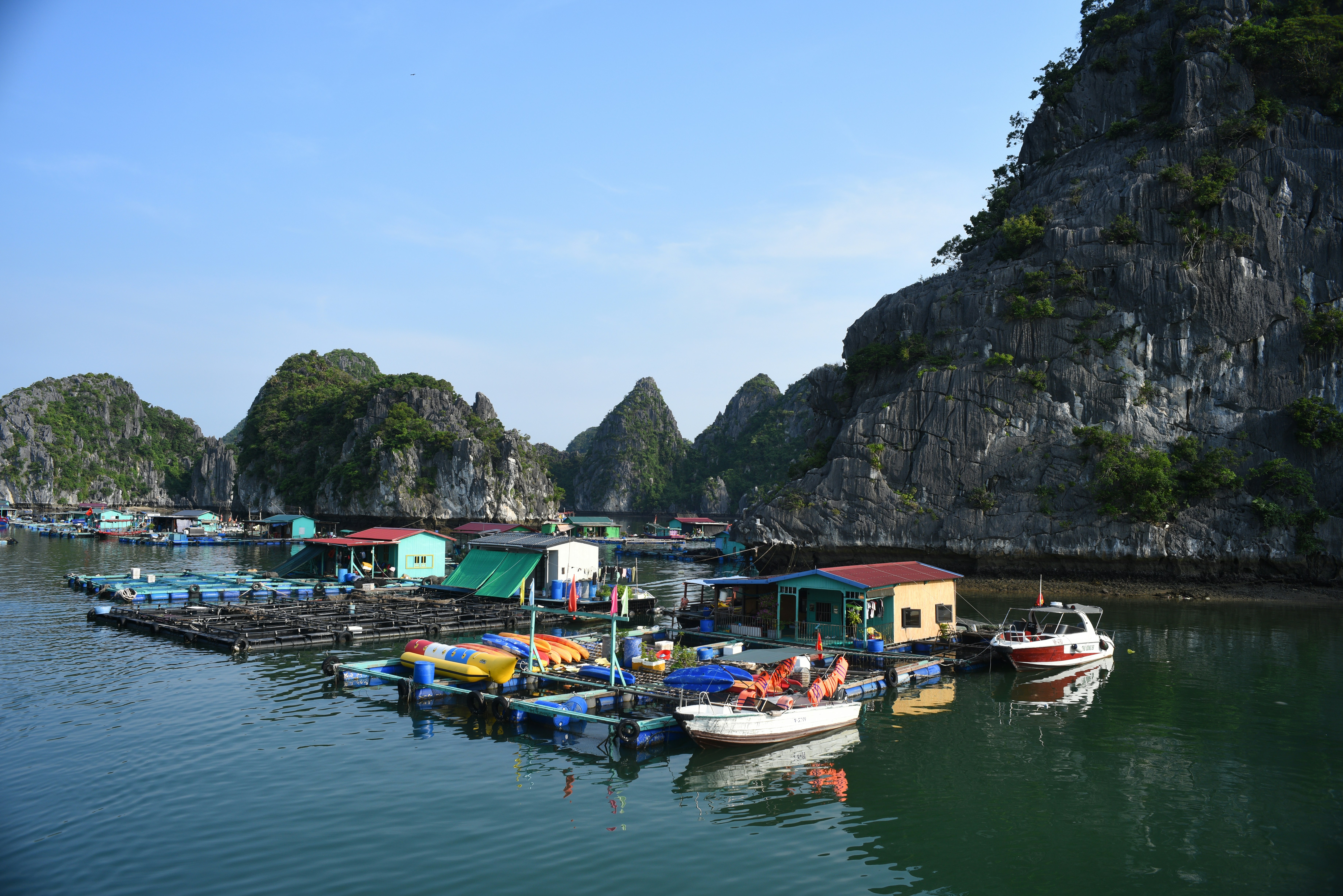 Floating village with colorful houses and boats among karst formations.