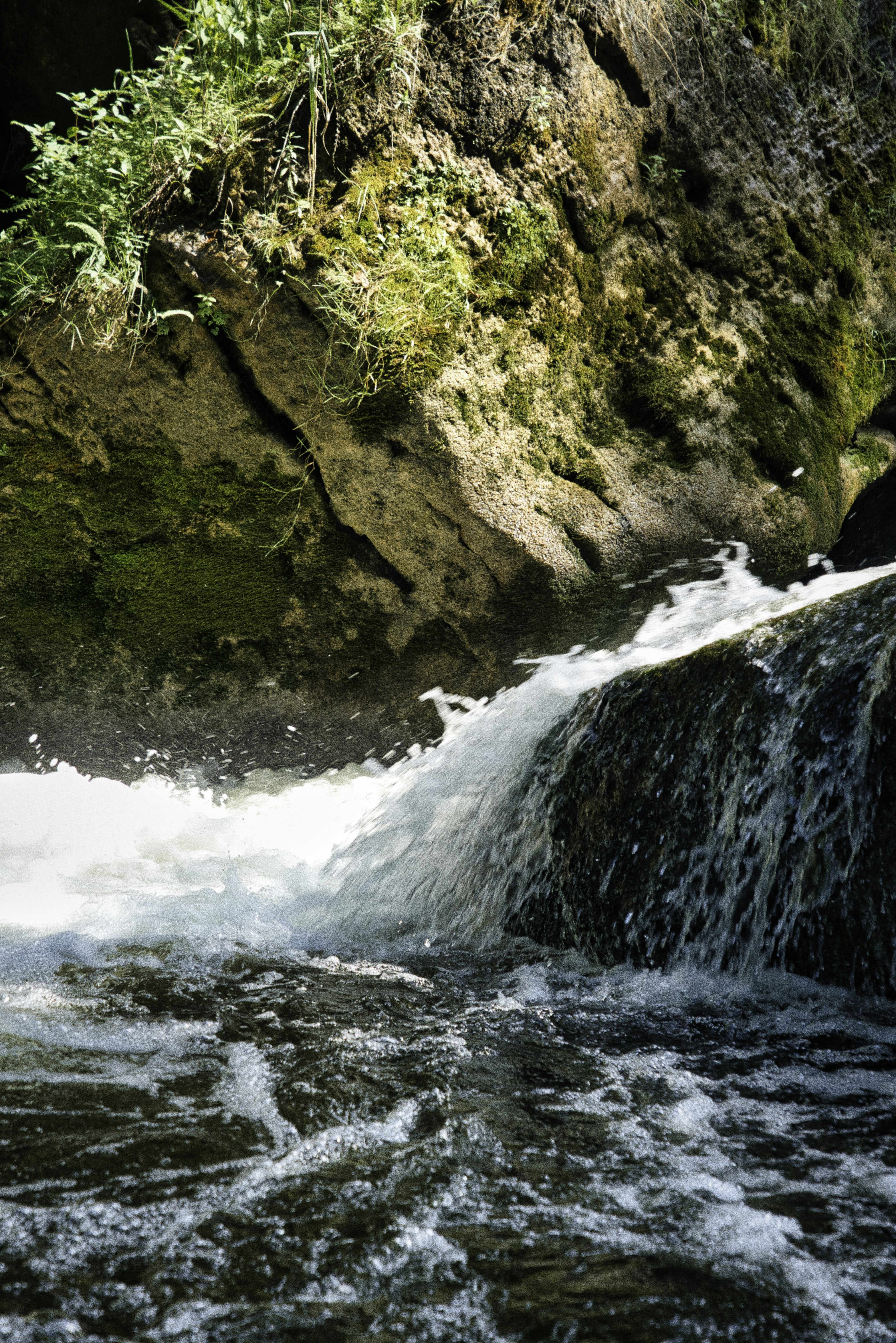 A small waterfall cascades over rocks in a forest.