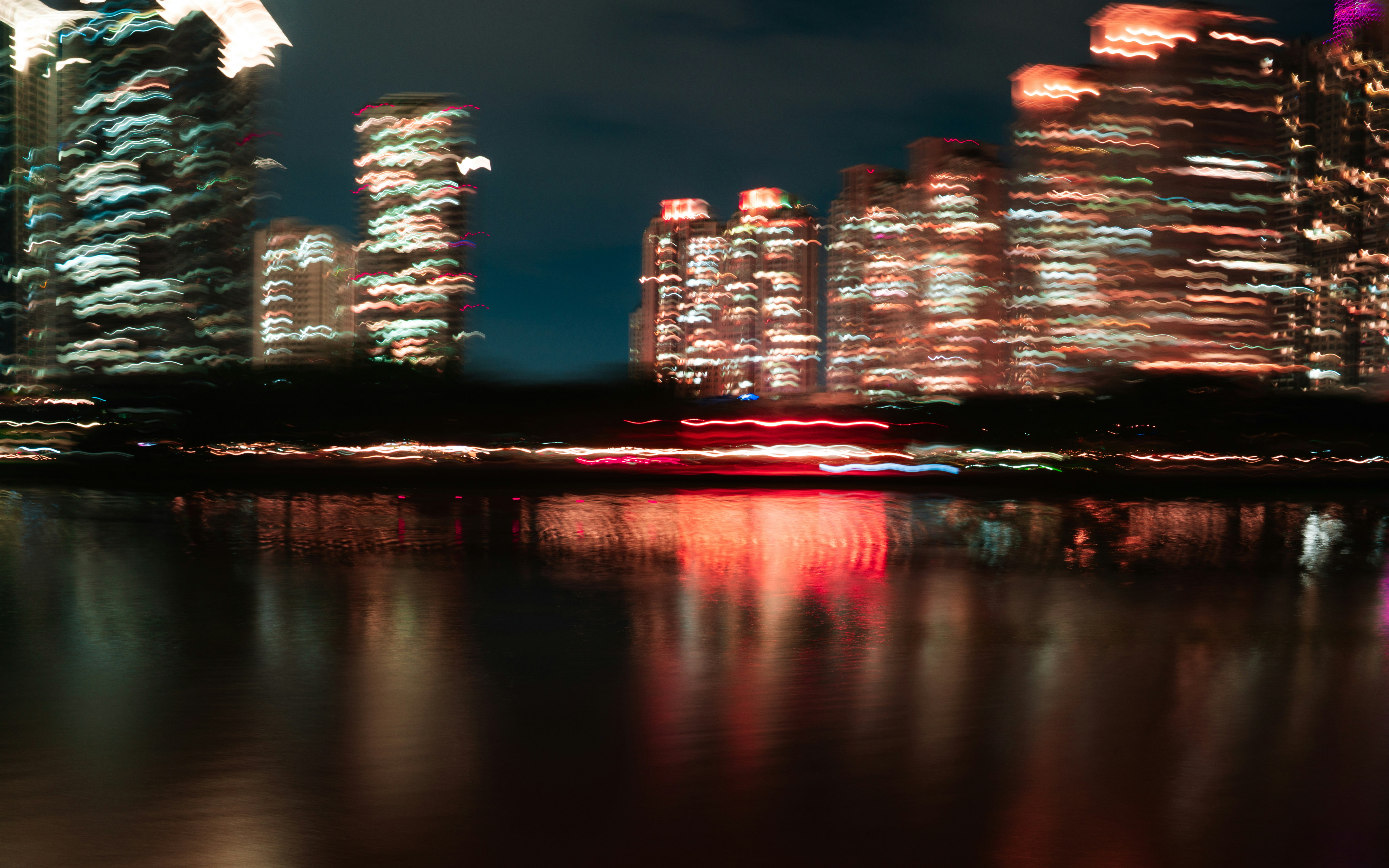 Blurry city lights reflected in dark water at night