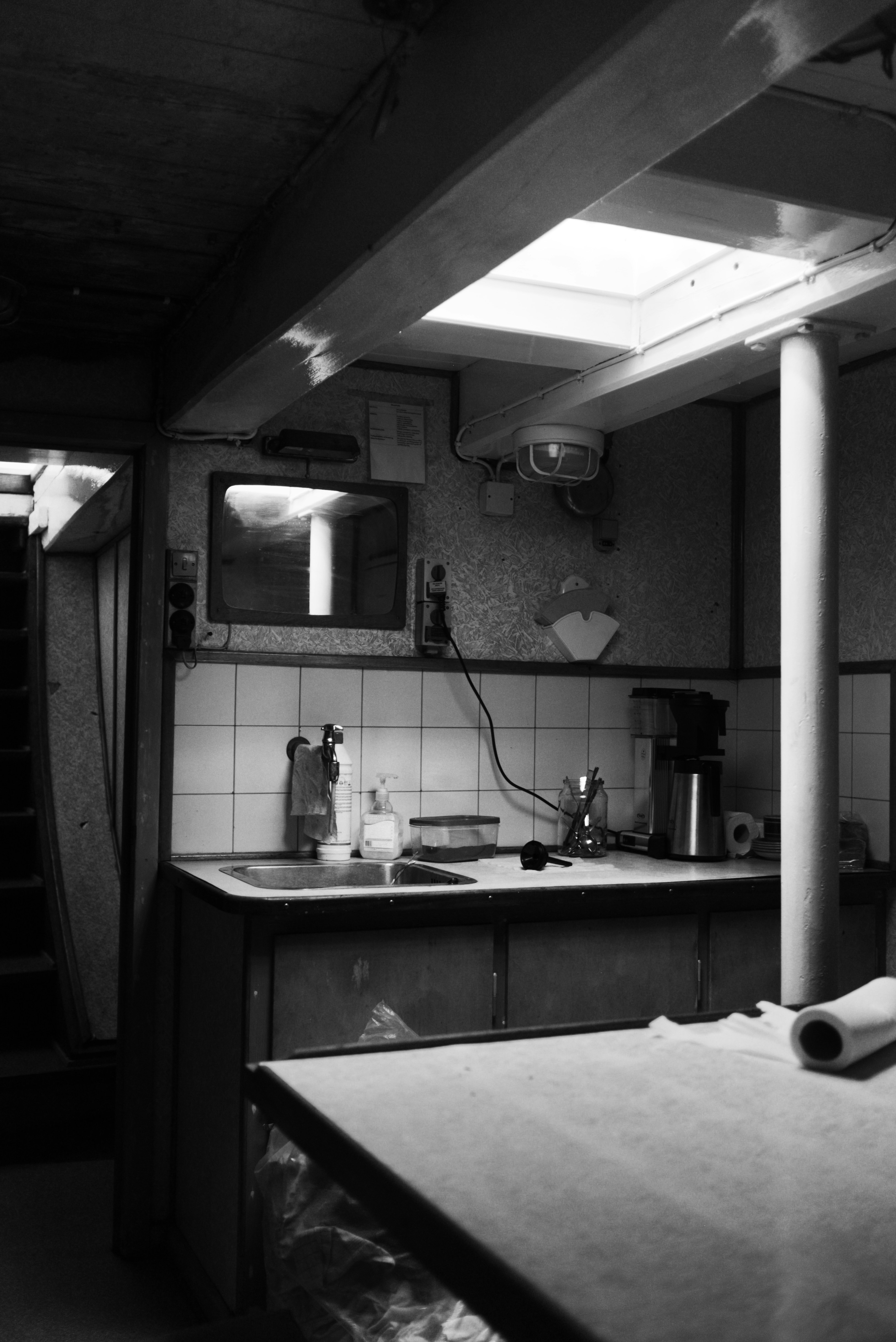 Eine schwach beleuchtete Küche mit Spüle und Kaffeemaschine.