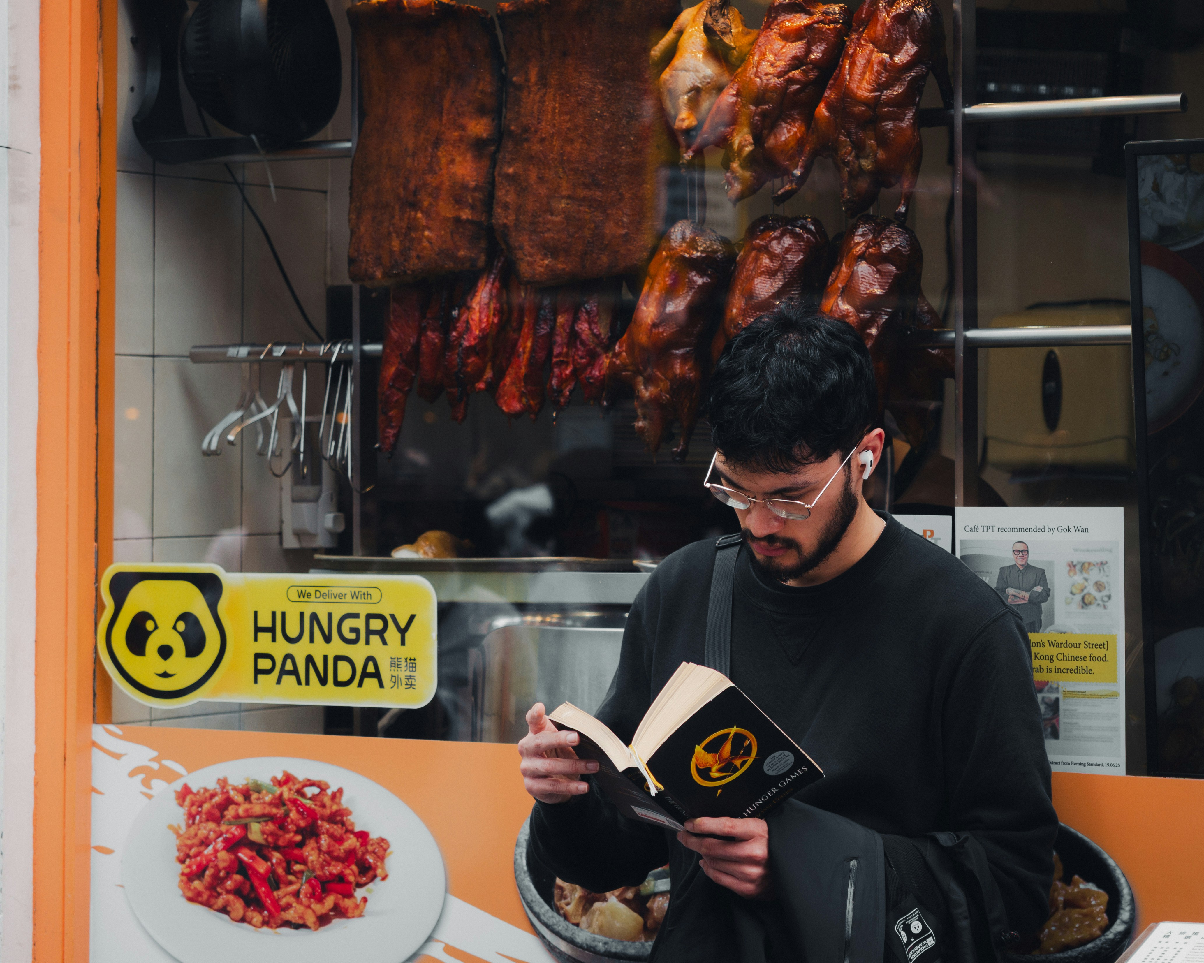 Man reading a book outside a restaurant