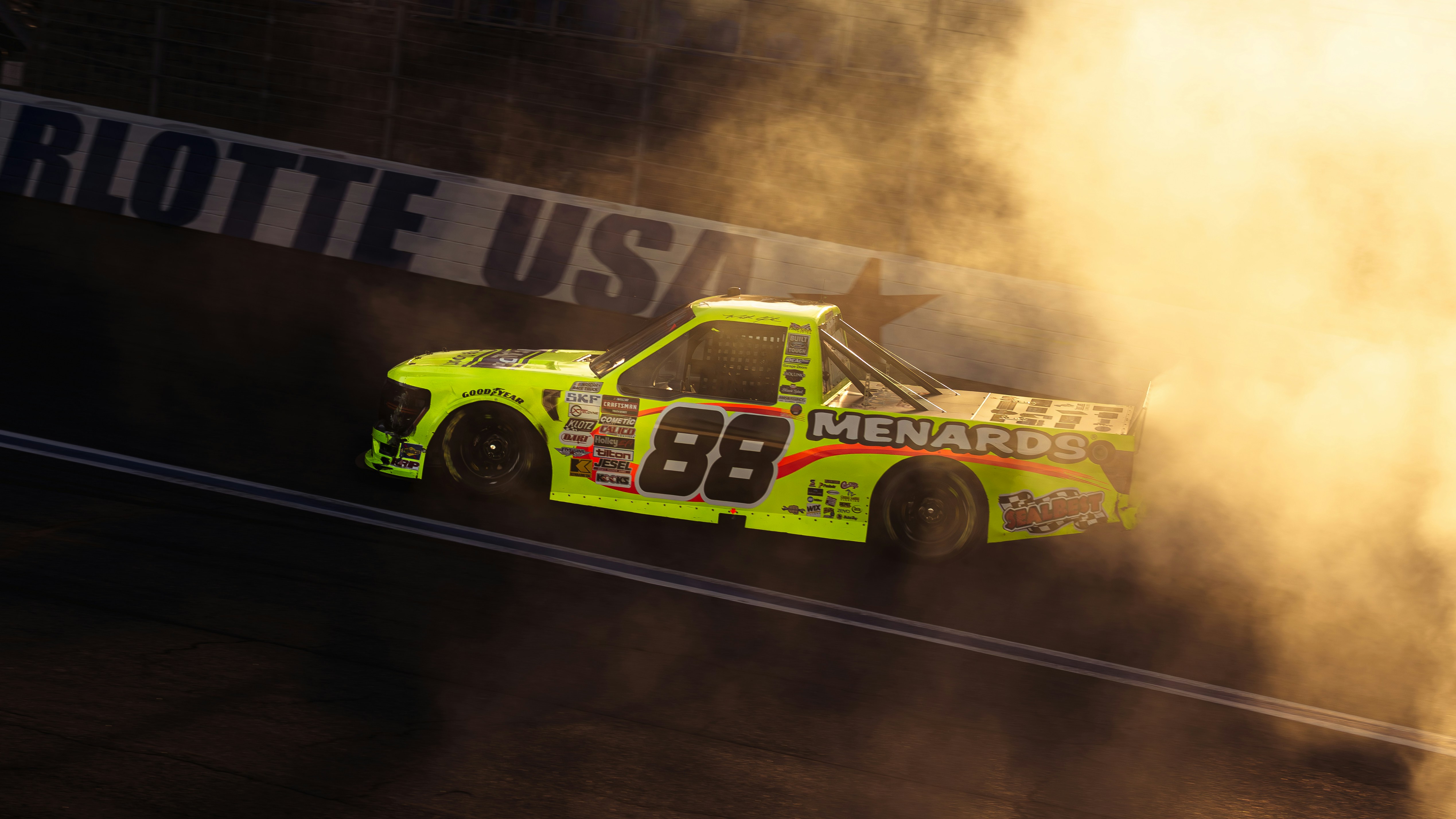 Race truck with number 88 emerges from smoke