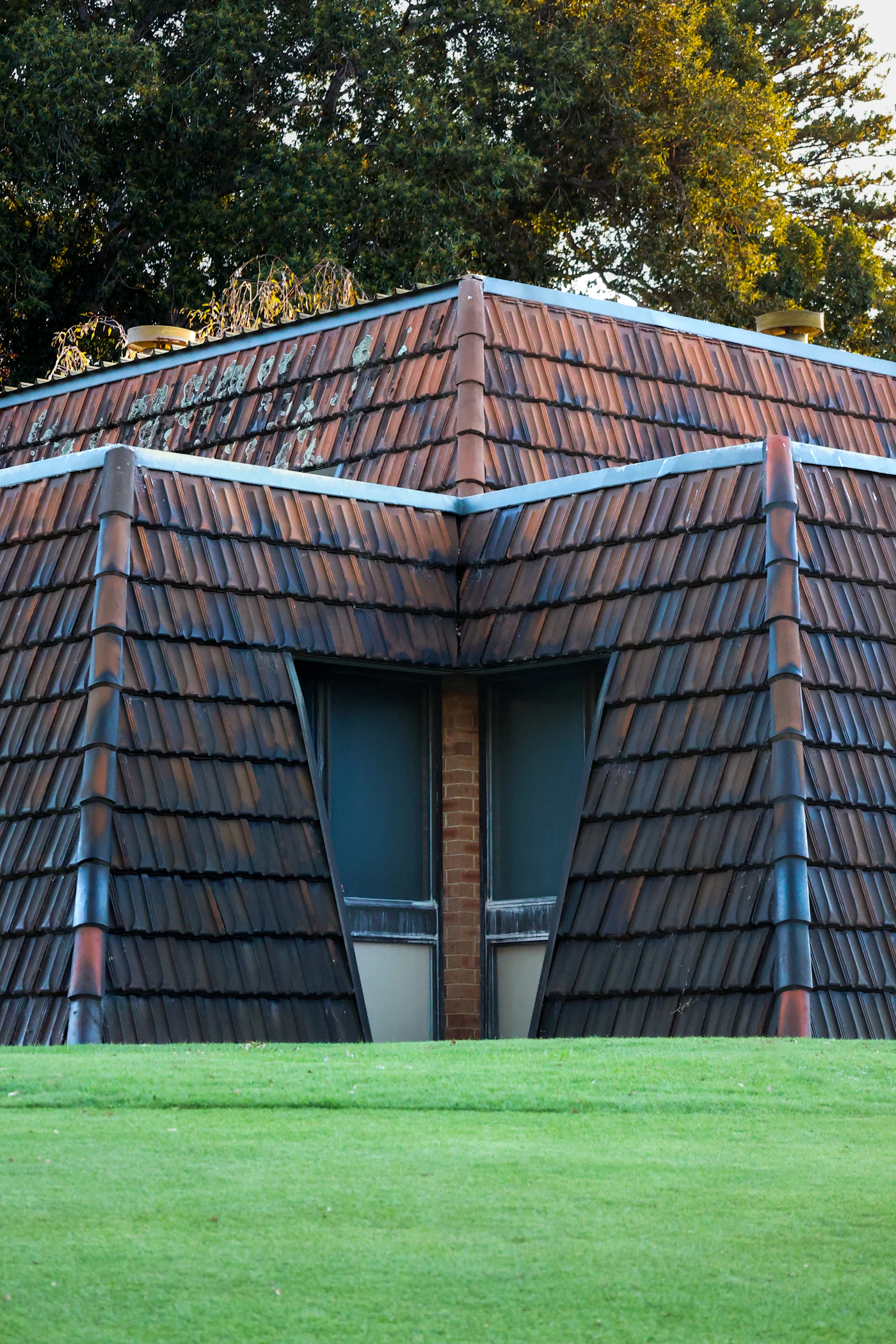 Tiled roof with penetrations and flashing details against a stormy sky
