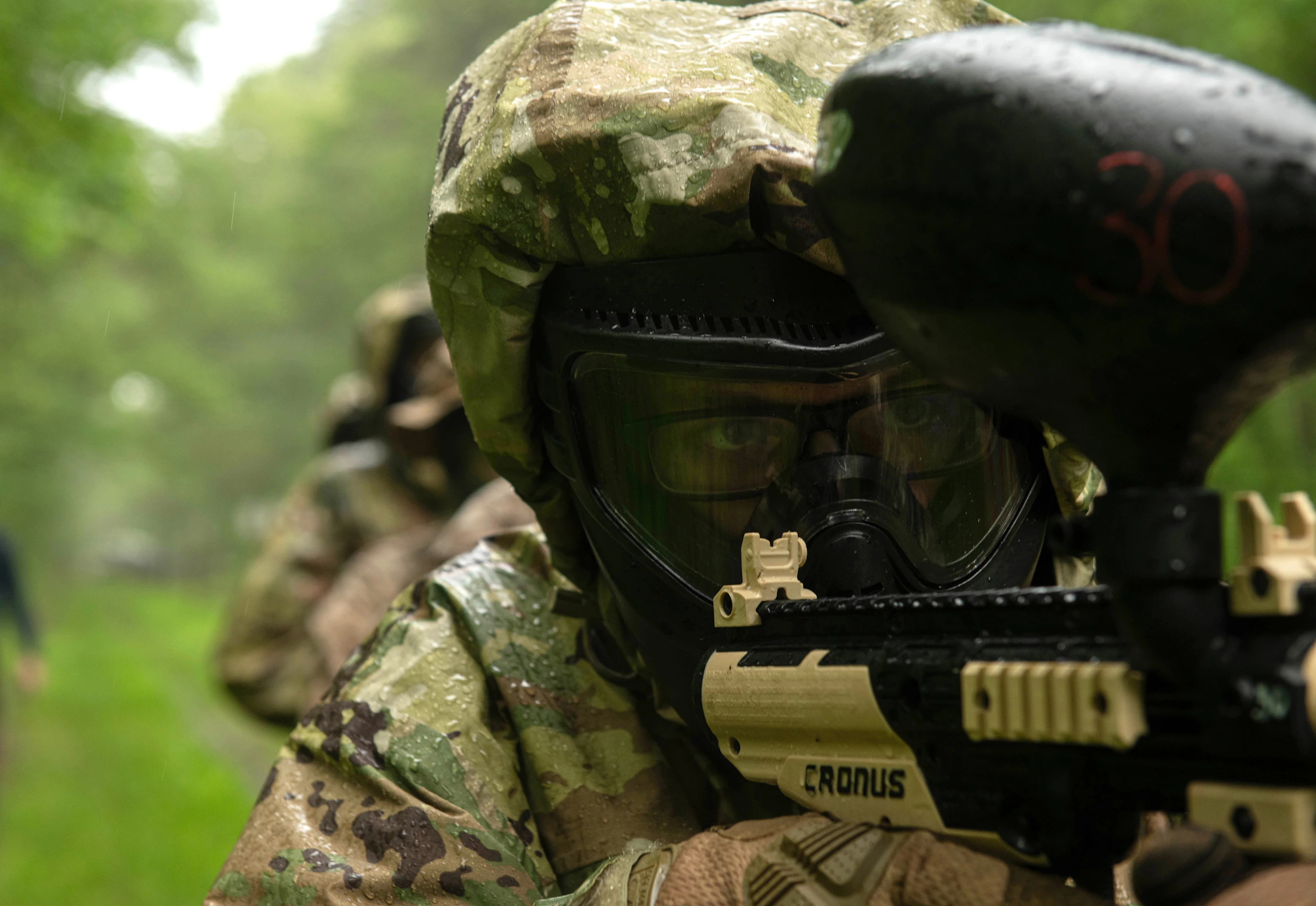 Joueur équipé d'un masque et d'un marqueur de paintball dans un environnement boisé
