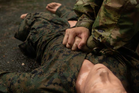 Soldier performing chest compressions on another soldier