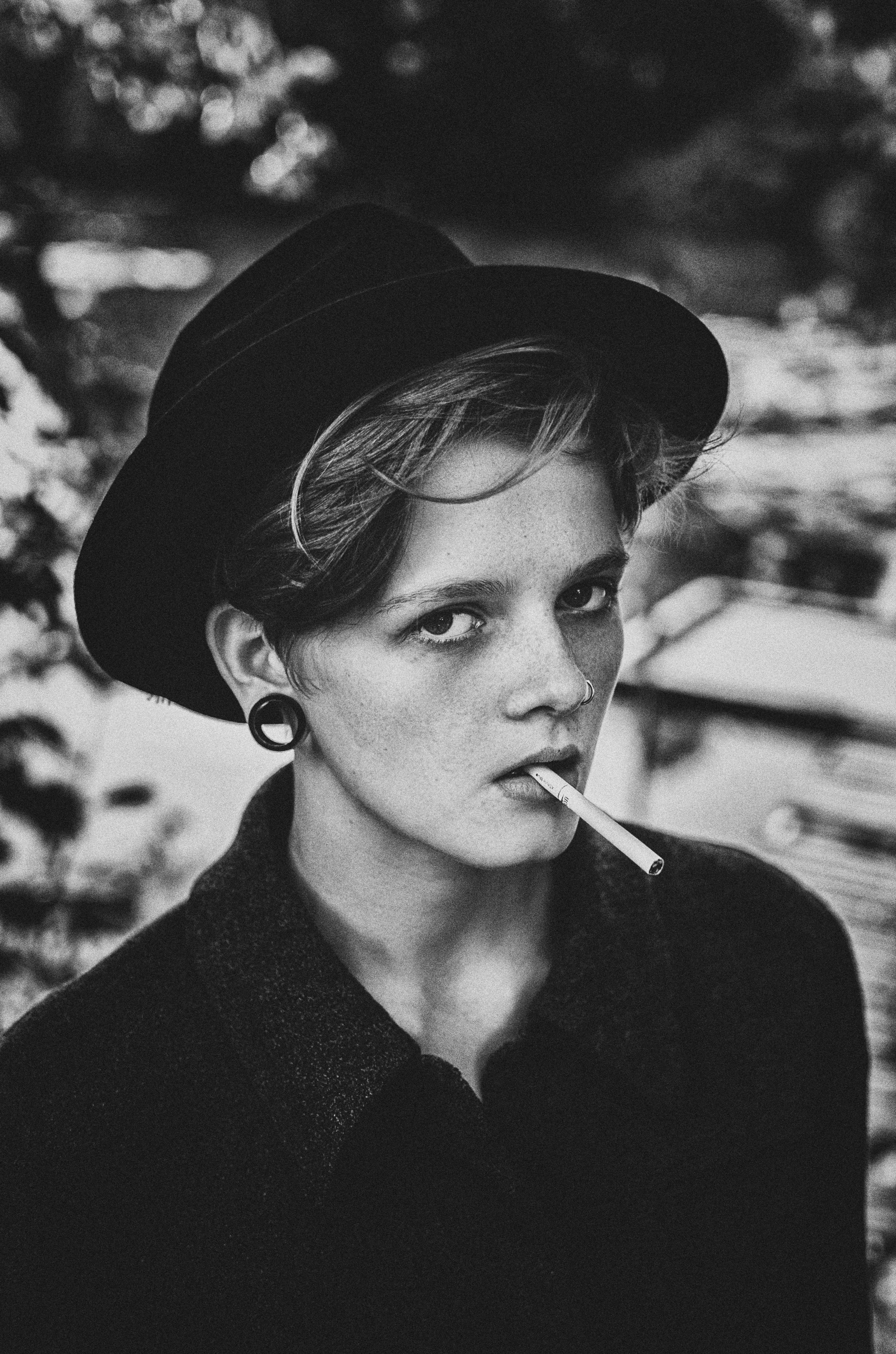 Young woman with hat smoking cigarette outdoors
