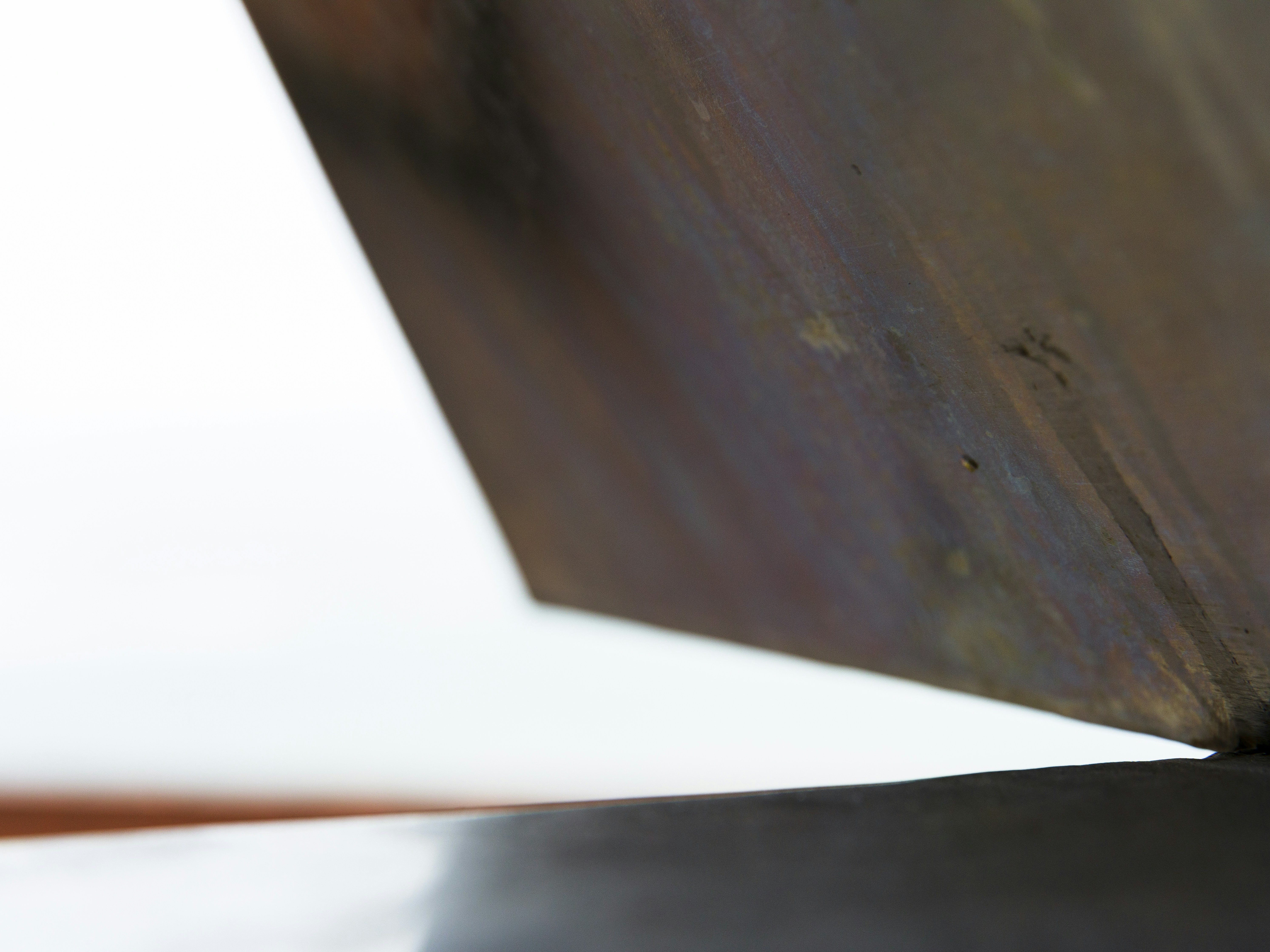 Close-up of weathered metal edge against white background