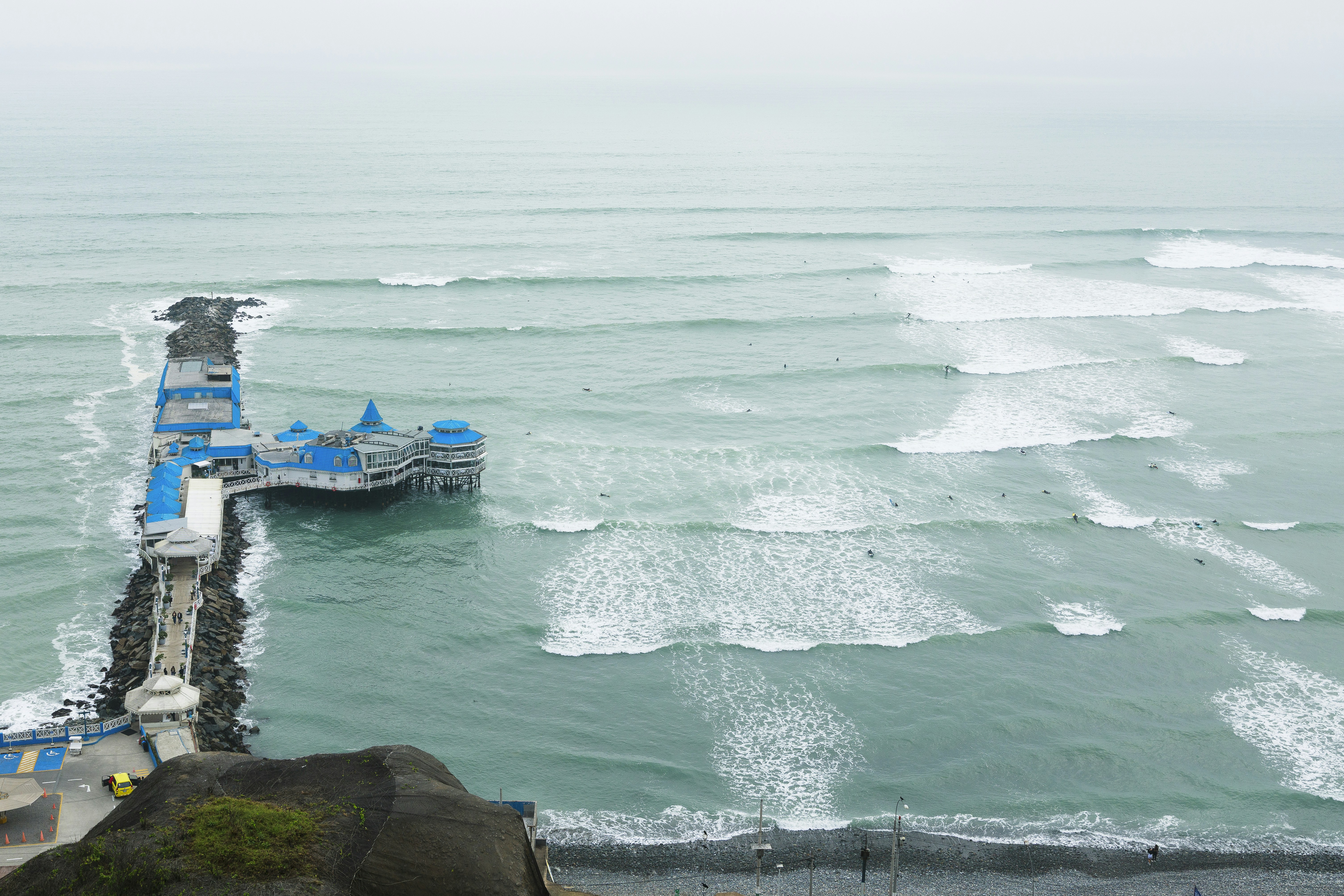 Pier with blue buildings jutting into the ocean waves
