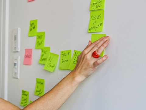 Hand placing a sticky note on a wall.