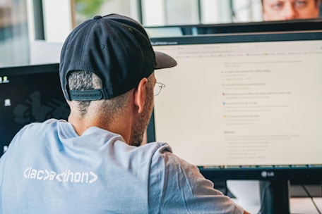 Man wearing baseball cap working at computer