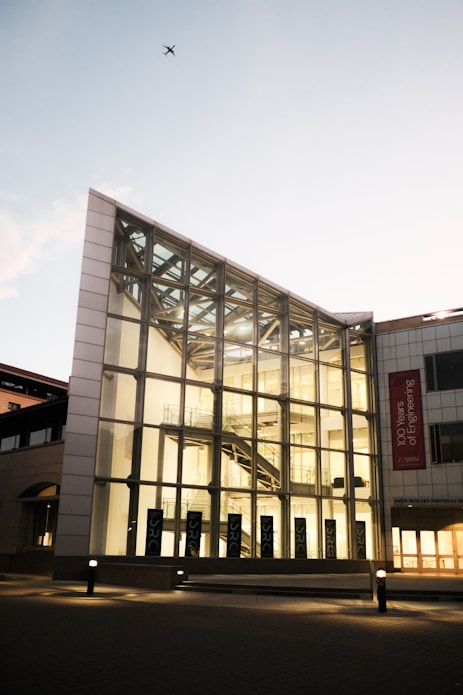 Modern glass building with a banner and airplane.