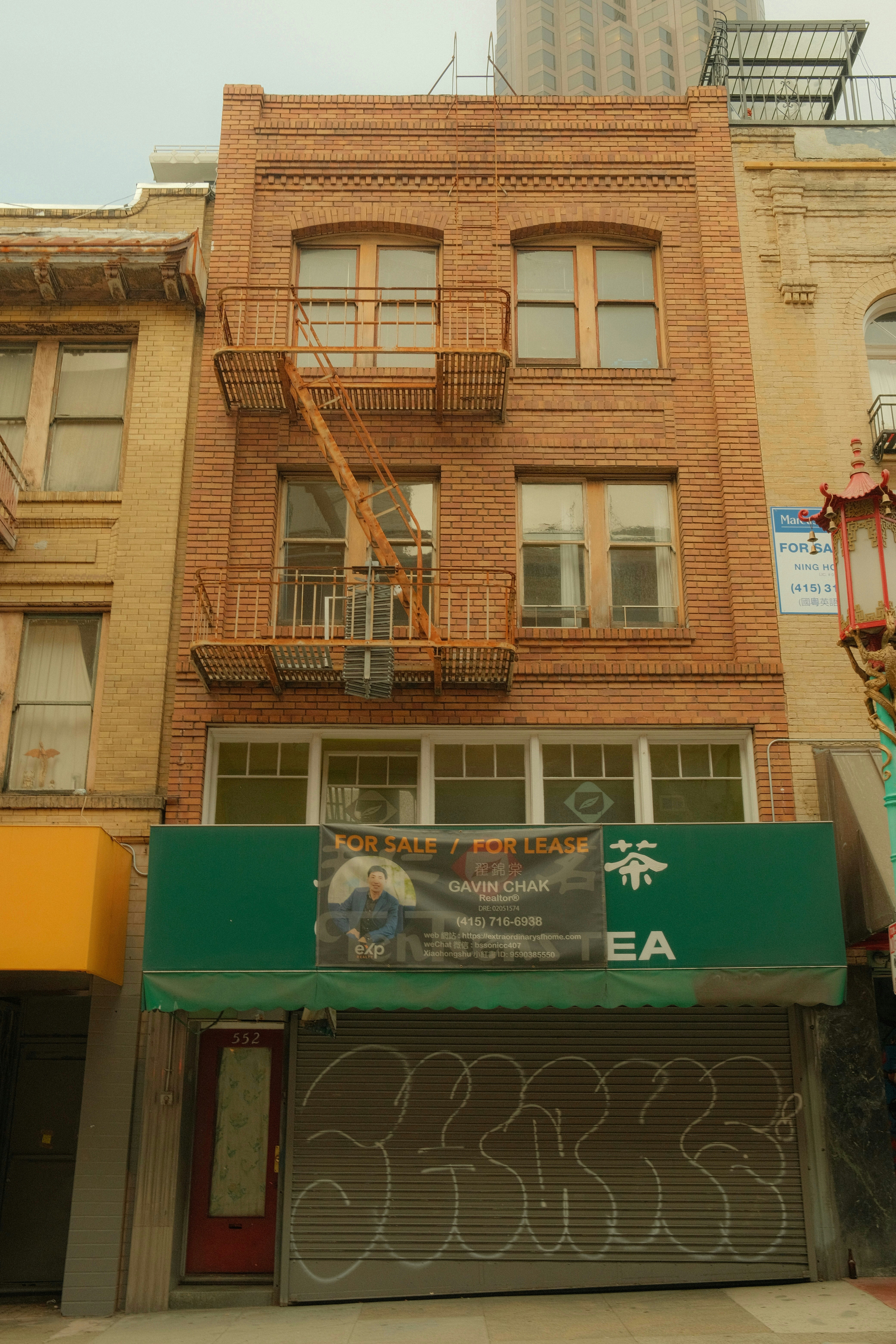 Brick building with green awning and graffiti covered roll-down gate.