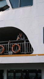 Man leans on railing of a white ferry boat