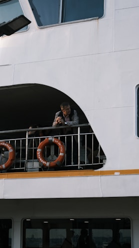 Man leans on railing of a white ferry boat