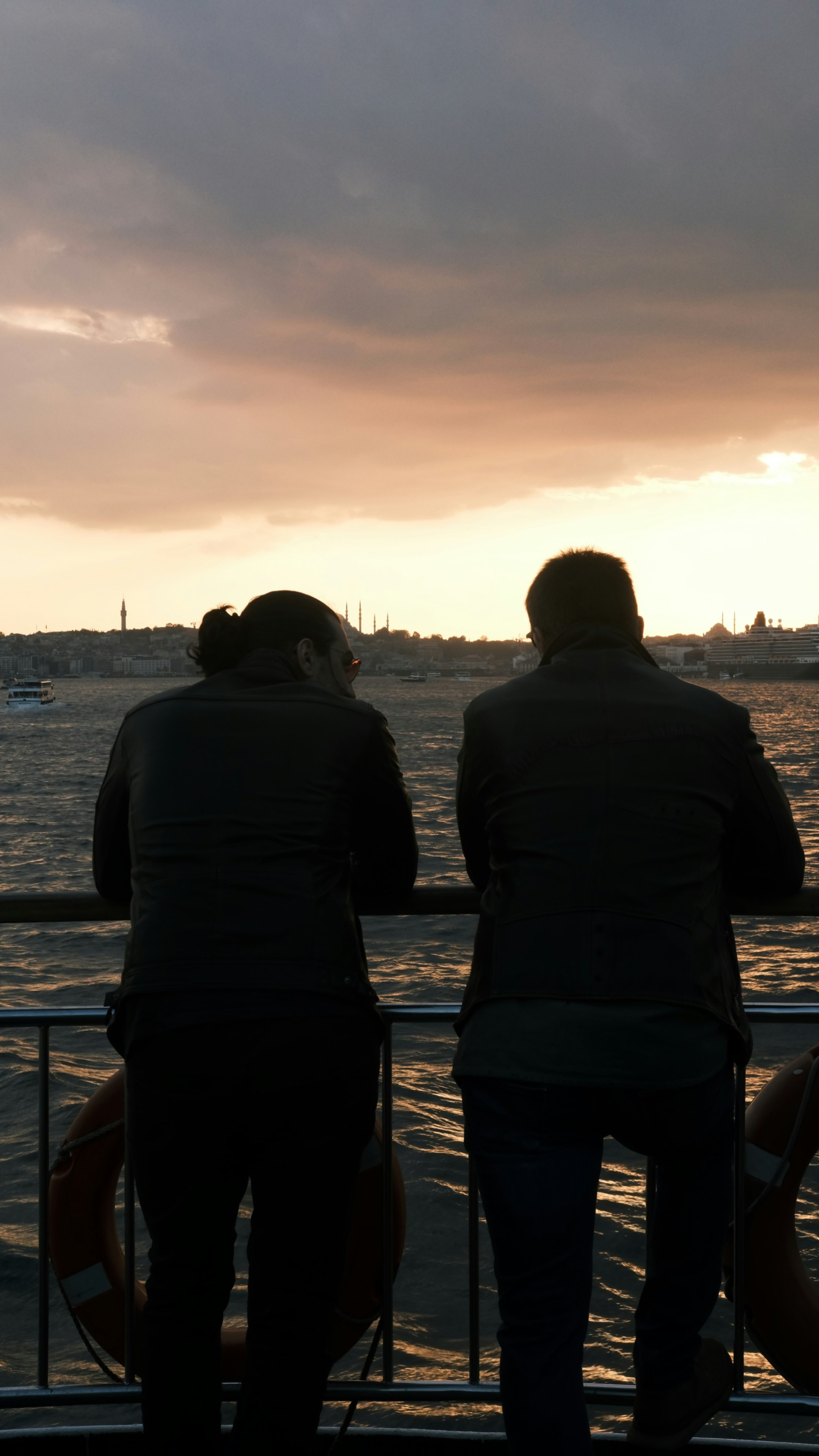 Due persone guardano il tramonto su uno skyline della città