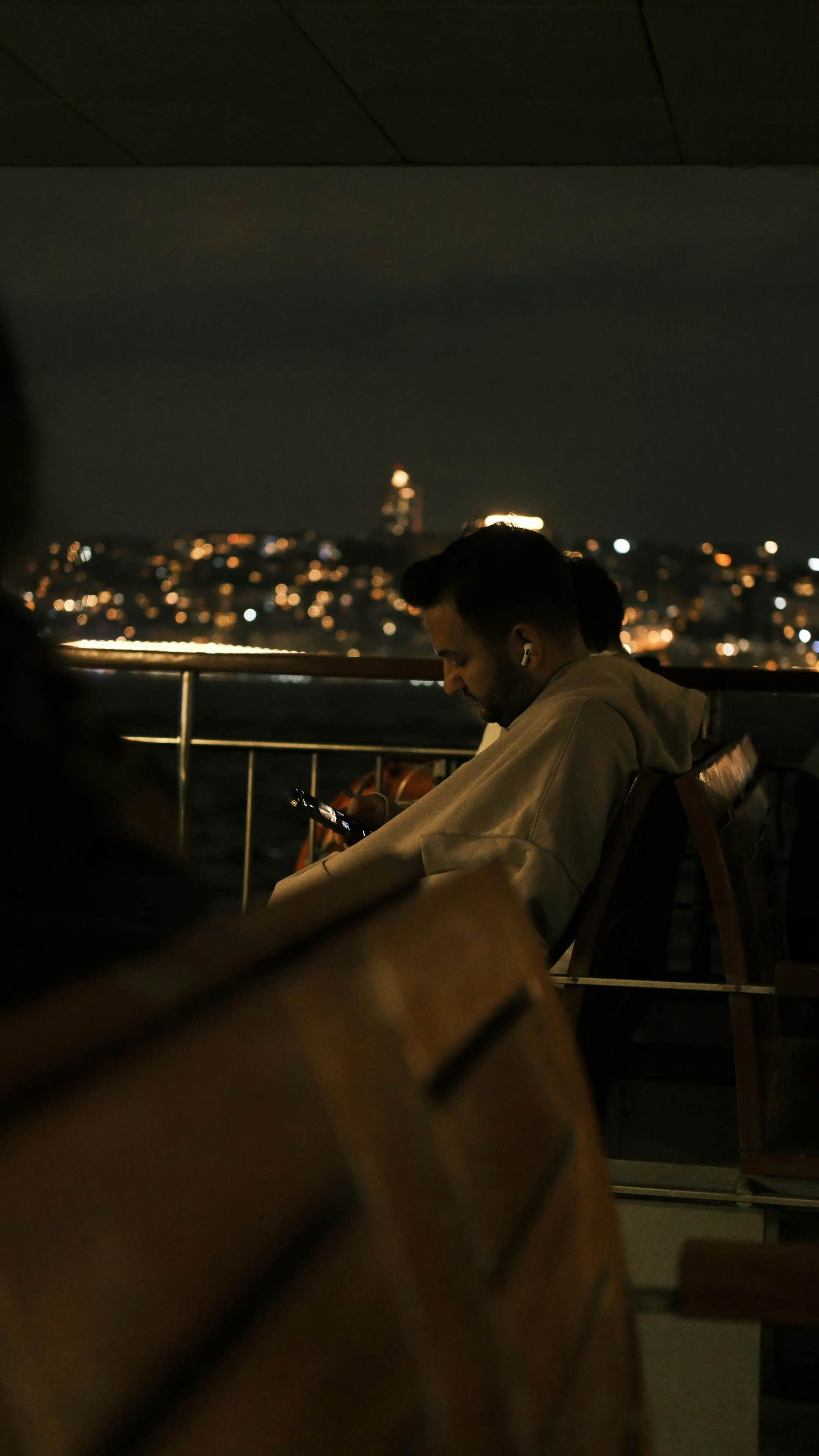 Man using phone on boat with city lights background