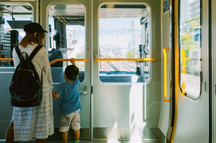 日本の電車内で窓の外を見る母親と幼い子ども