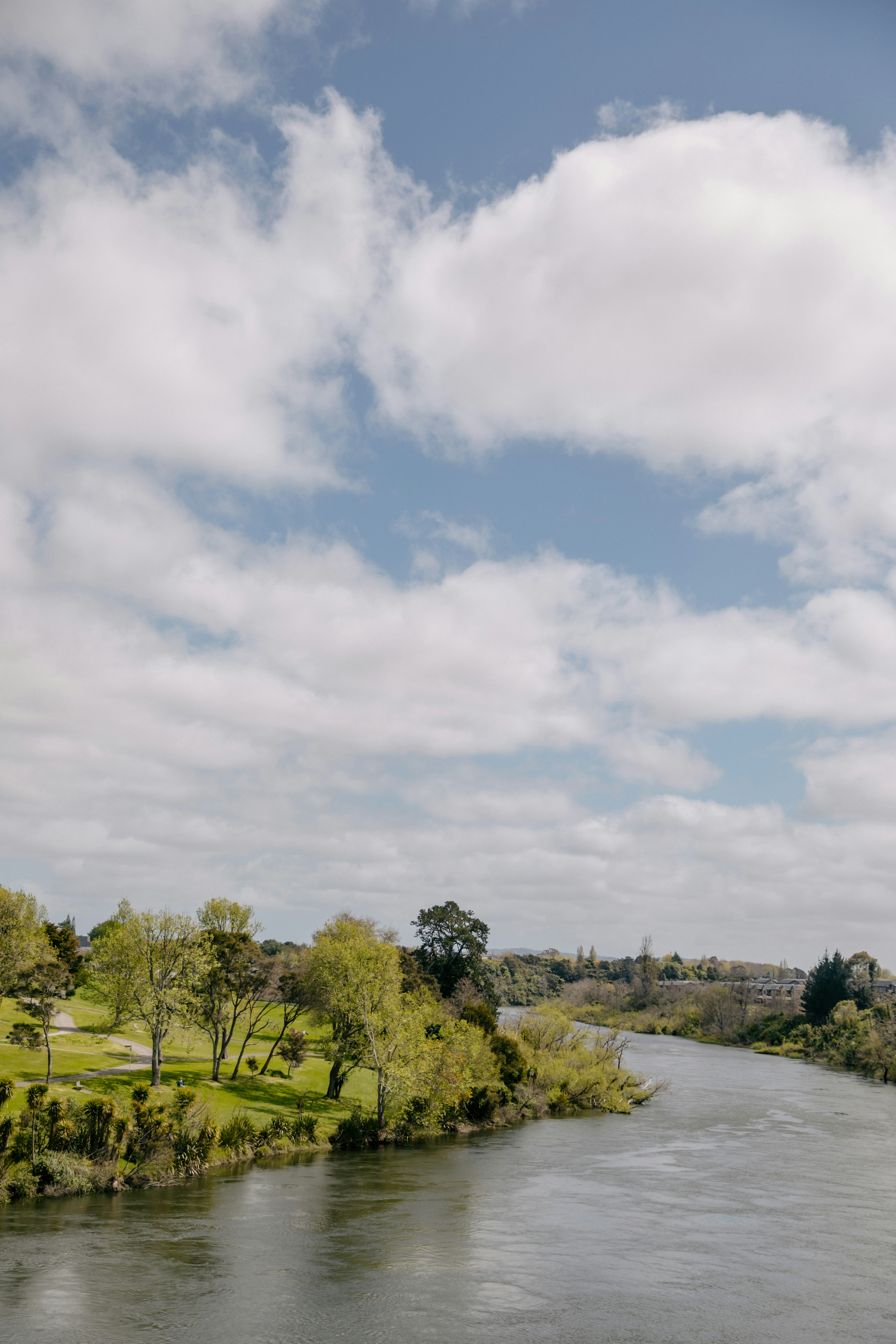 A wide river flows through a green landscape under clouds.