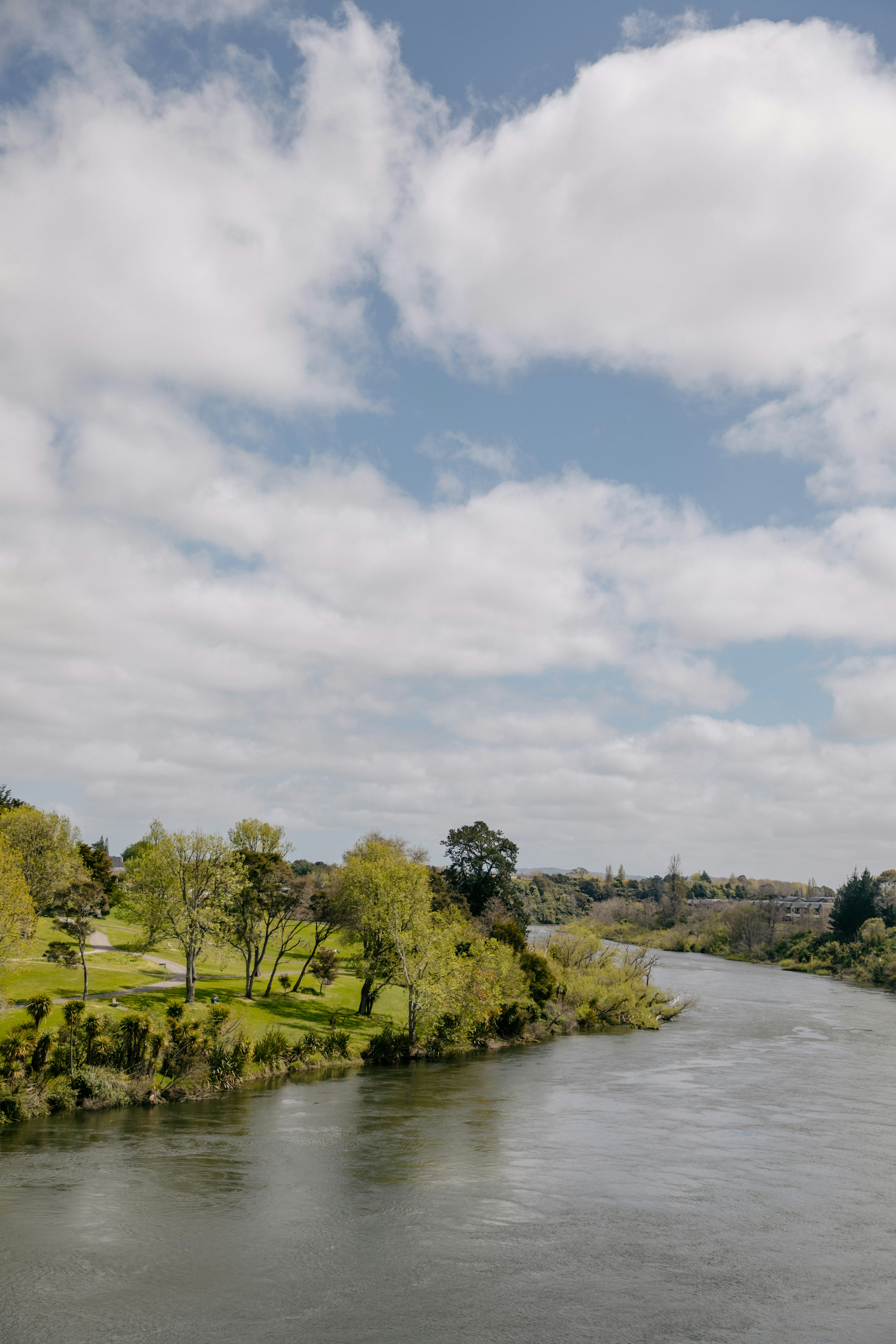 A wide river flows through a park landscape.