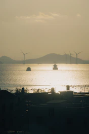 Navios e turbinas eólicas ao entardecer, representando soluções sustentáveis em logística internacio