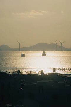 Navios e turbinas eólicas ao entardecer, representando soluções sustentáveis em logística internacio