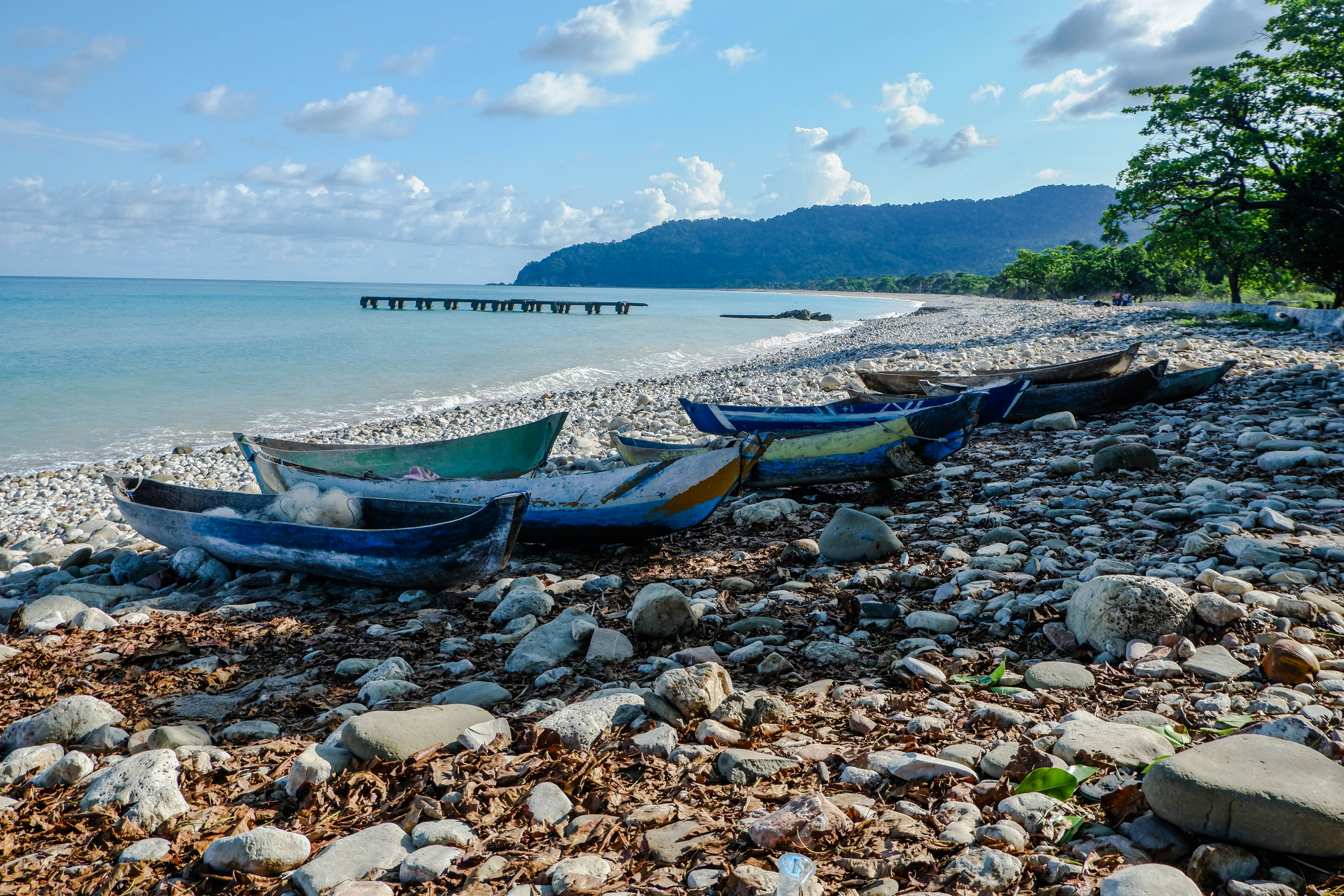 Several colorful boats rest on a rocky beach.