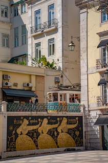 Historic tram passes buildings with tiled mural