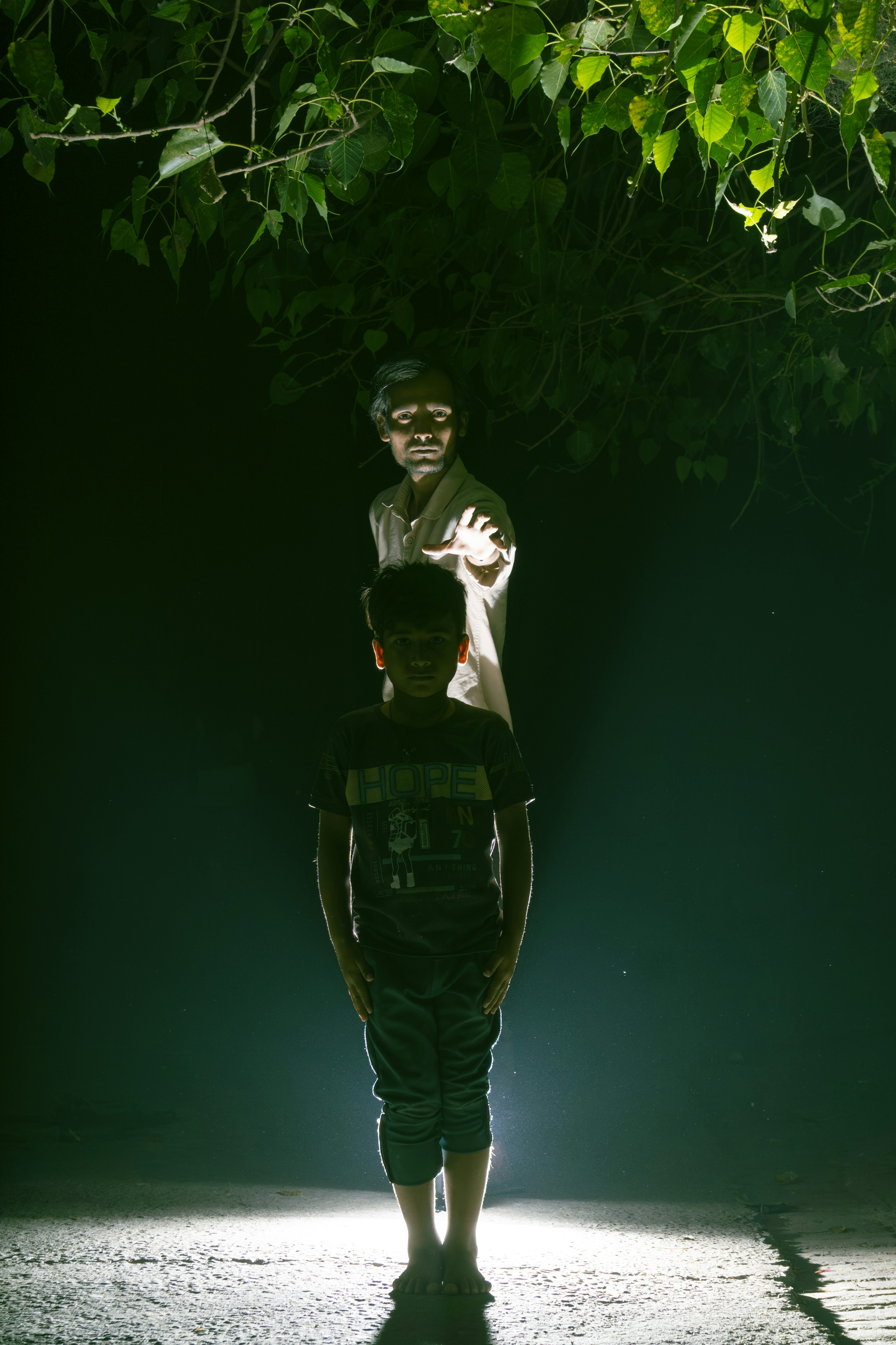 Two figures stand illuminated in the dark.