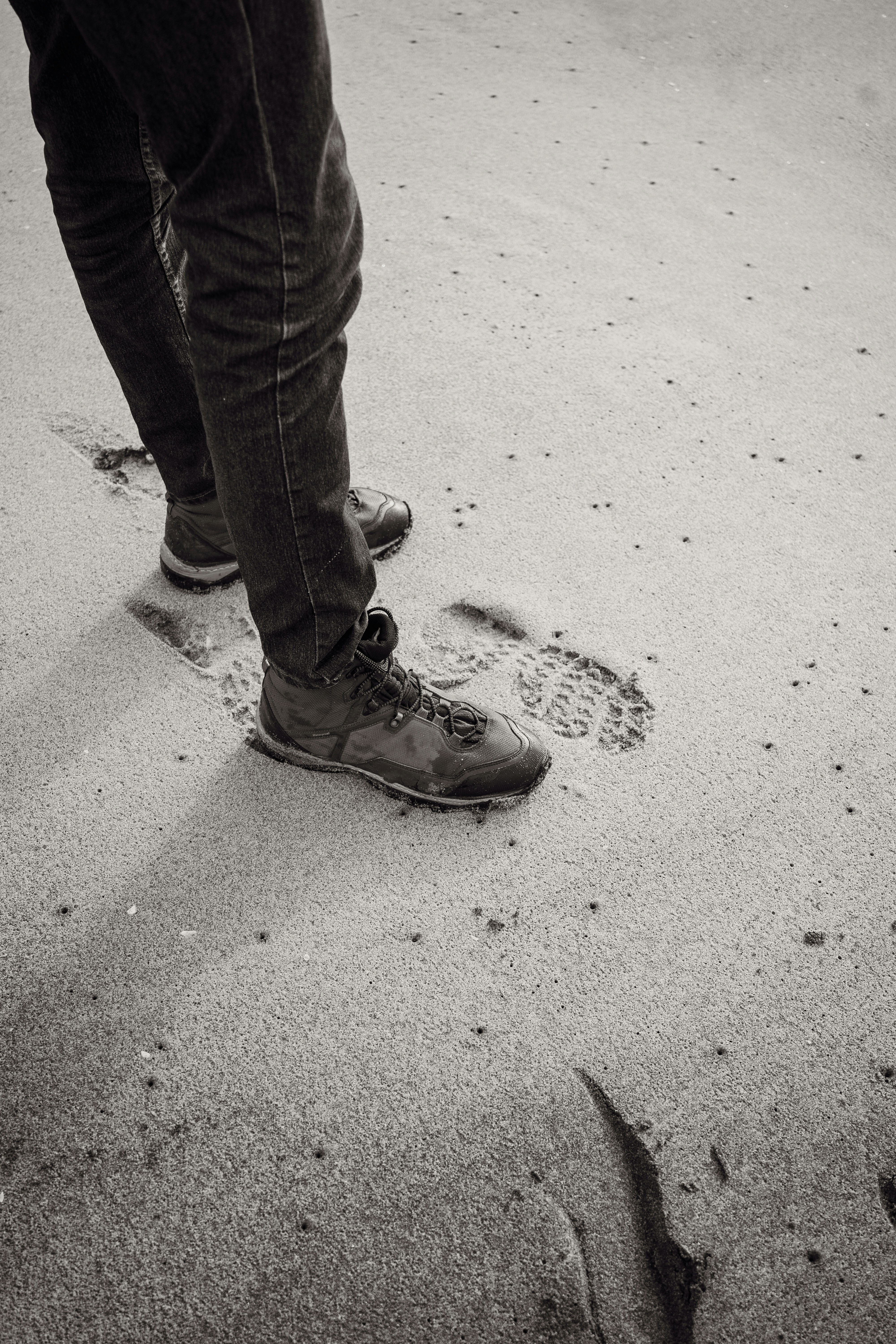 Person's legs and feet standing on sand