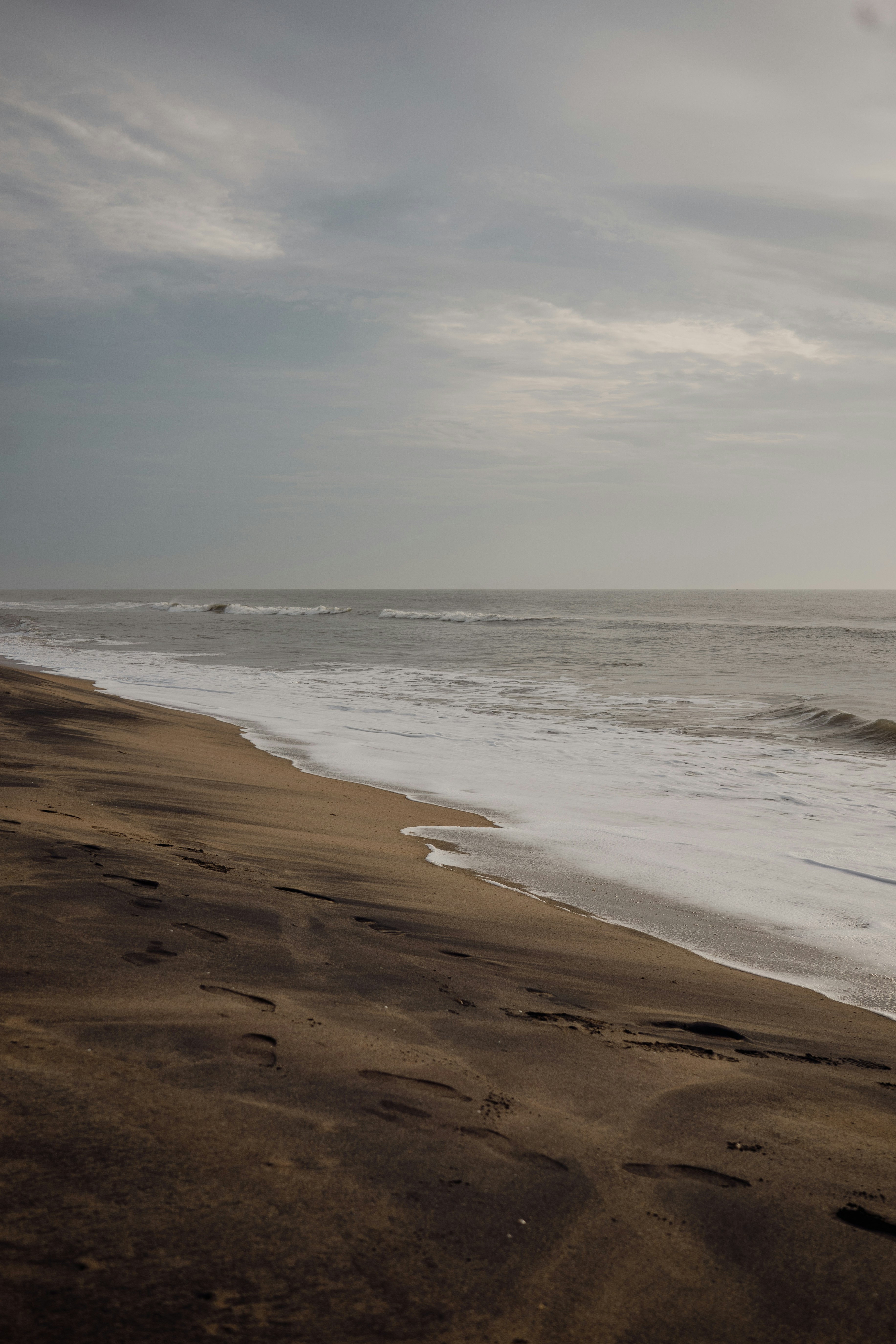 Waves crashing on a sandy beach under cloudy sky