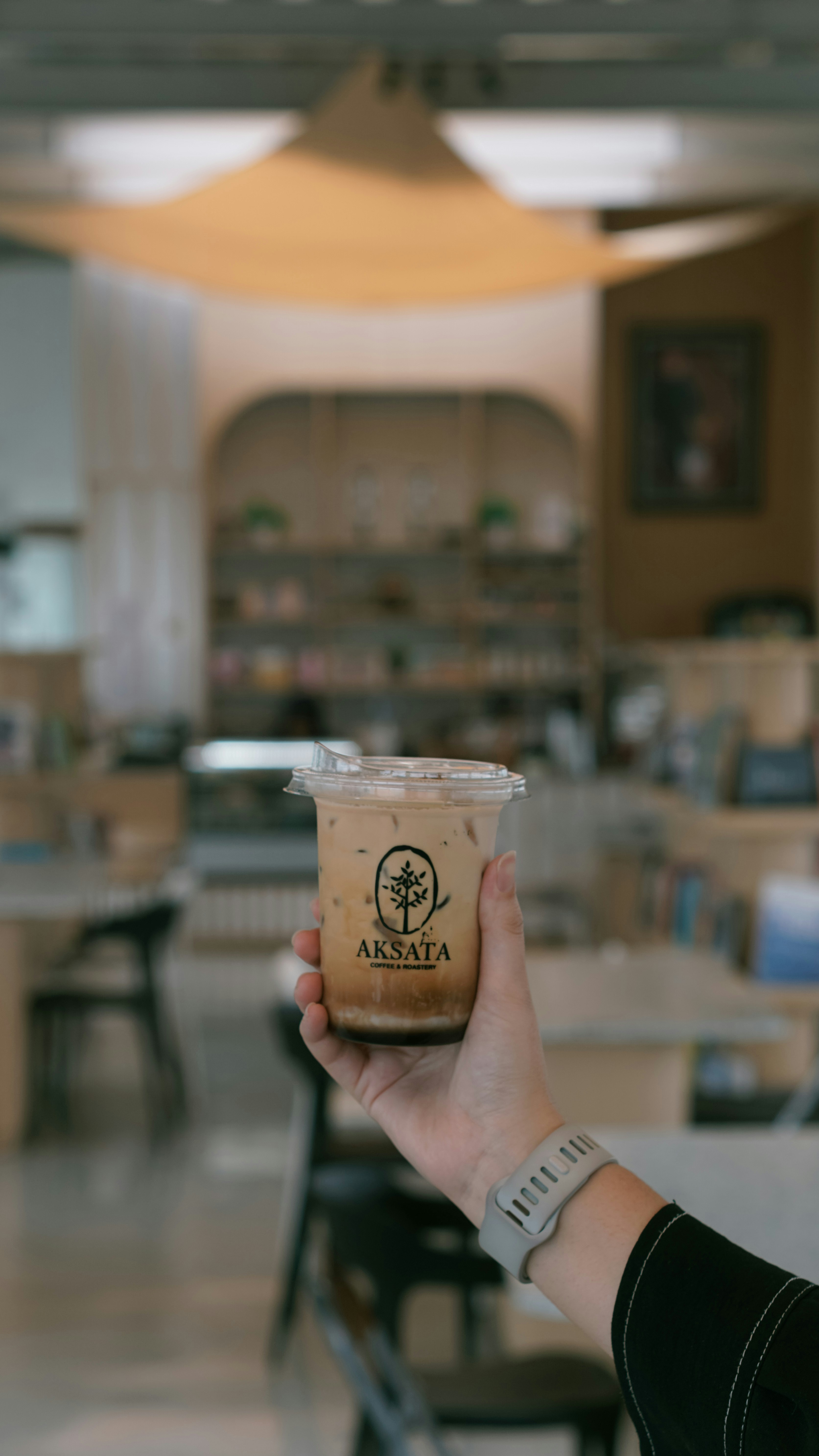 Hand holding iced coffee in a cafe