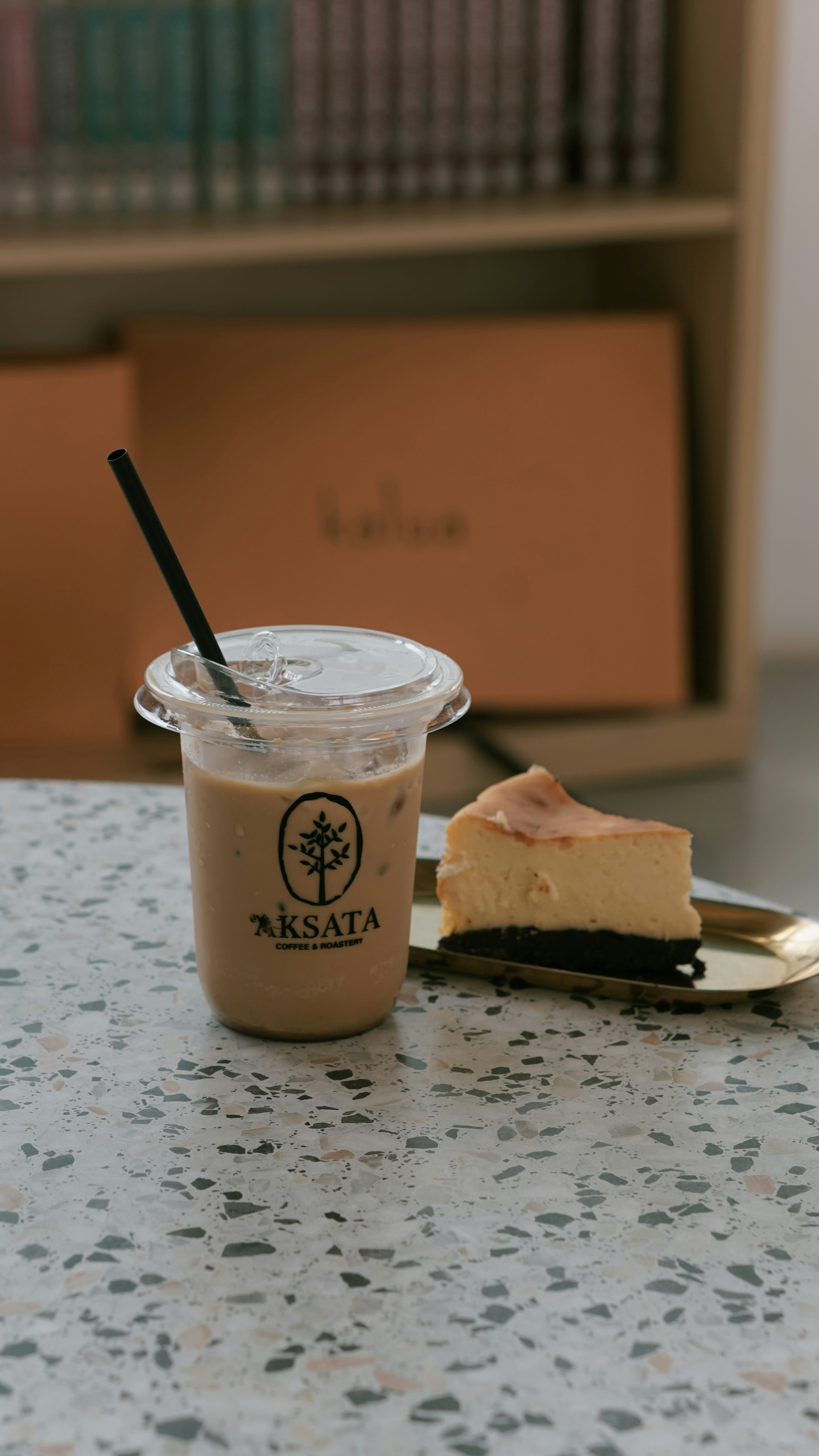 Iced coffee and cheesecake on a speckled table.