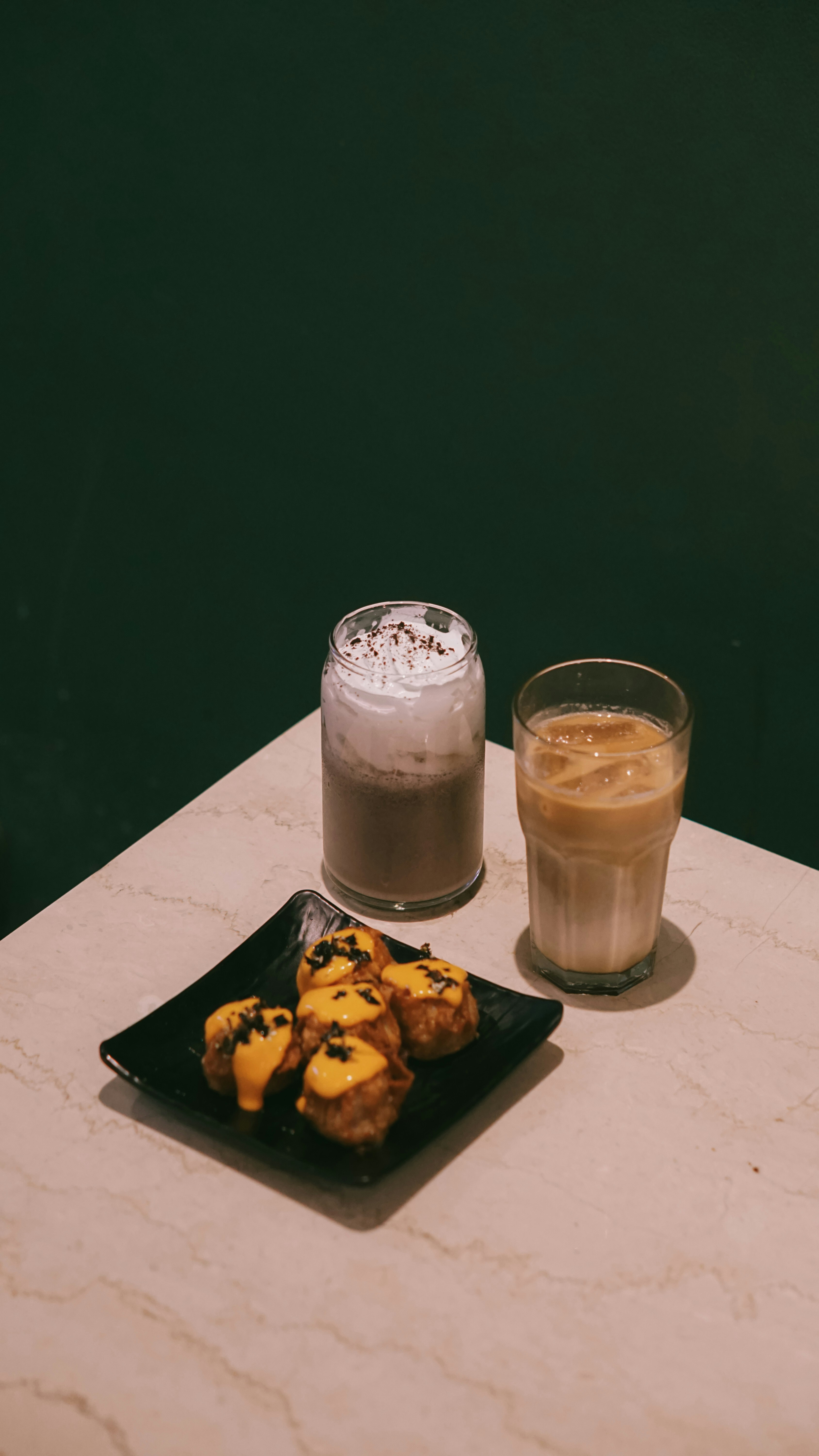 Two iced coffees and fried snacks on a table.