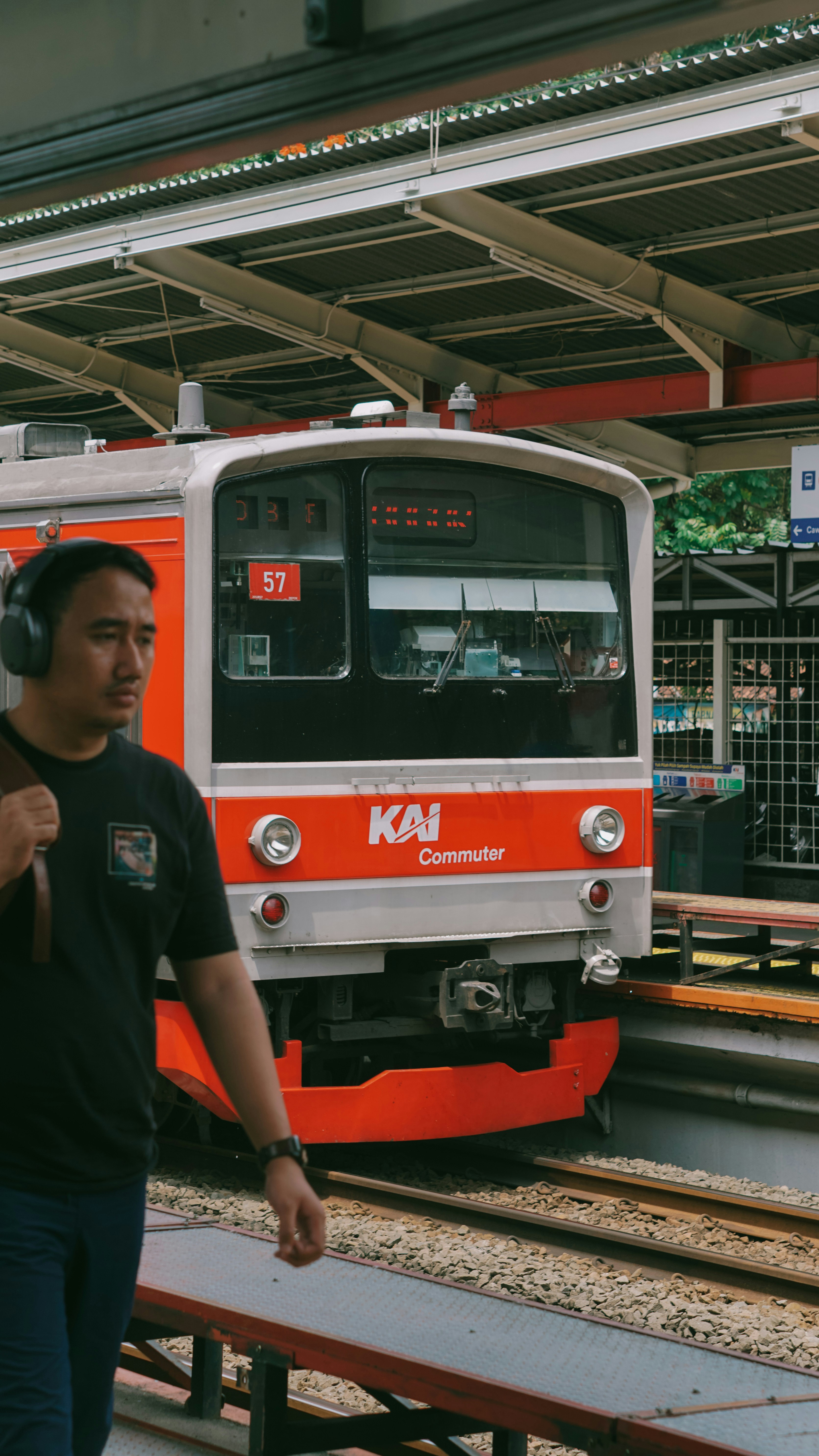 Man with headphones walks past train at station.