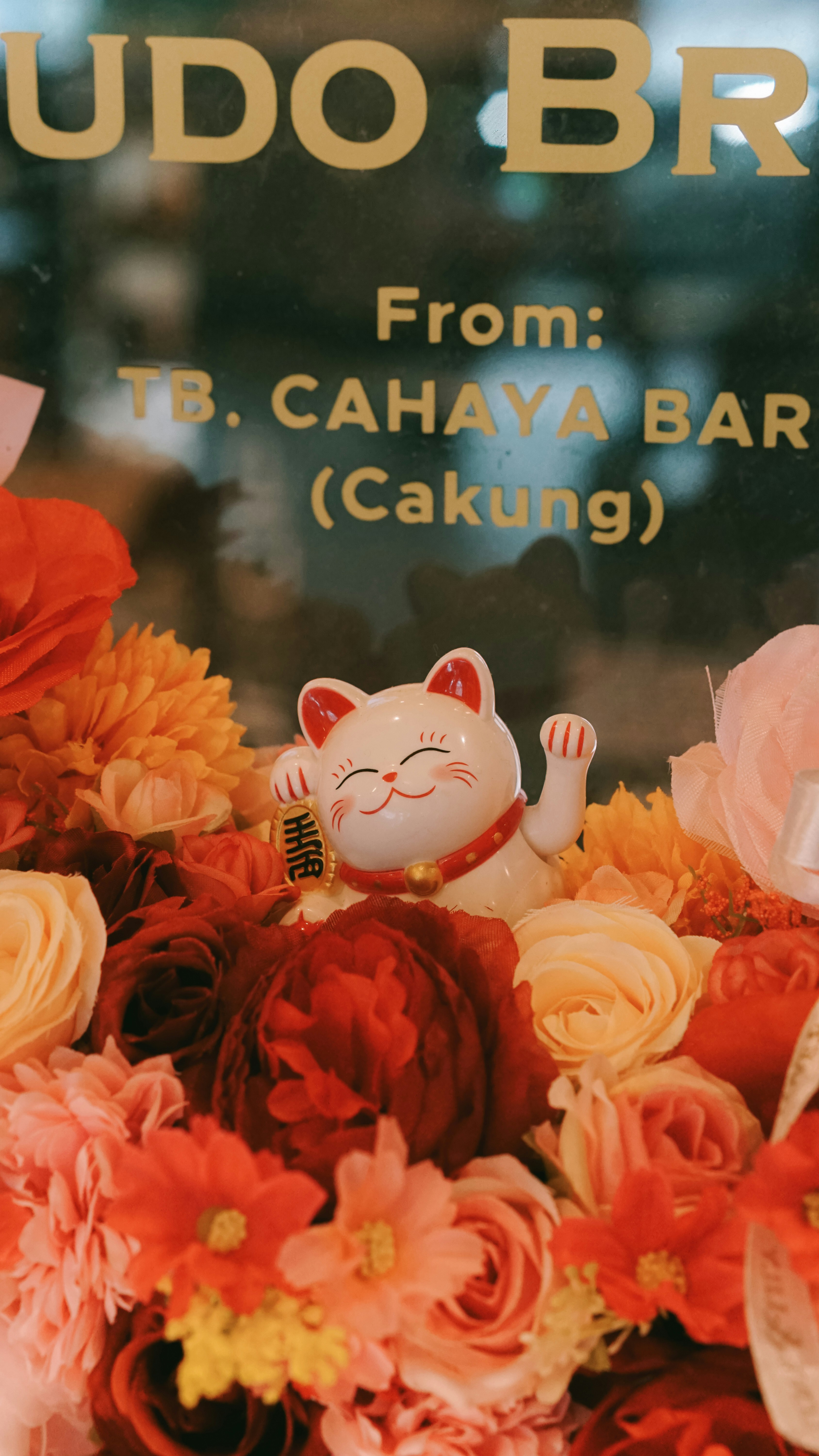 Maneki-neko cat figurine among colorful flowers