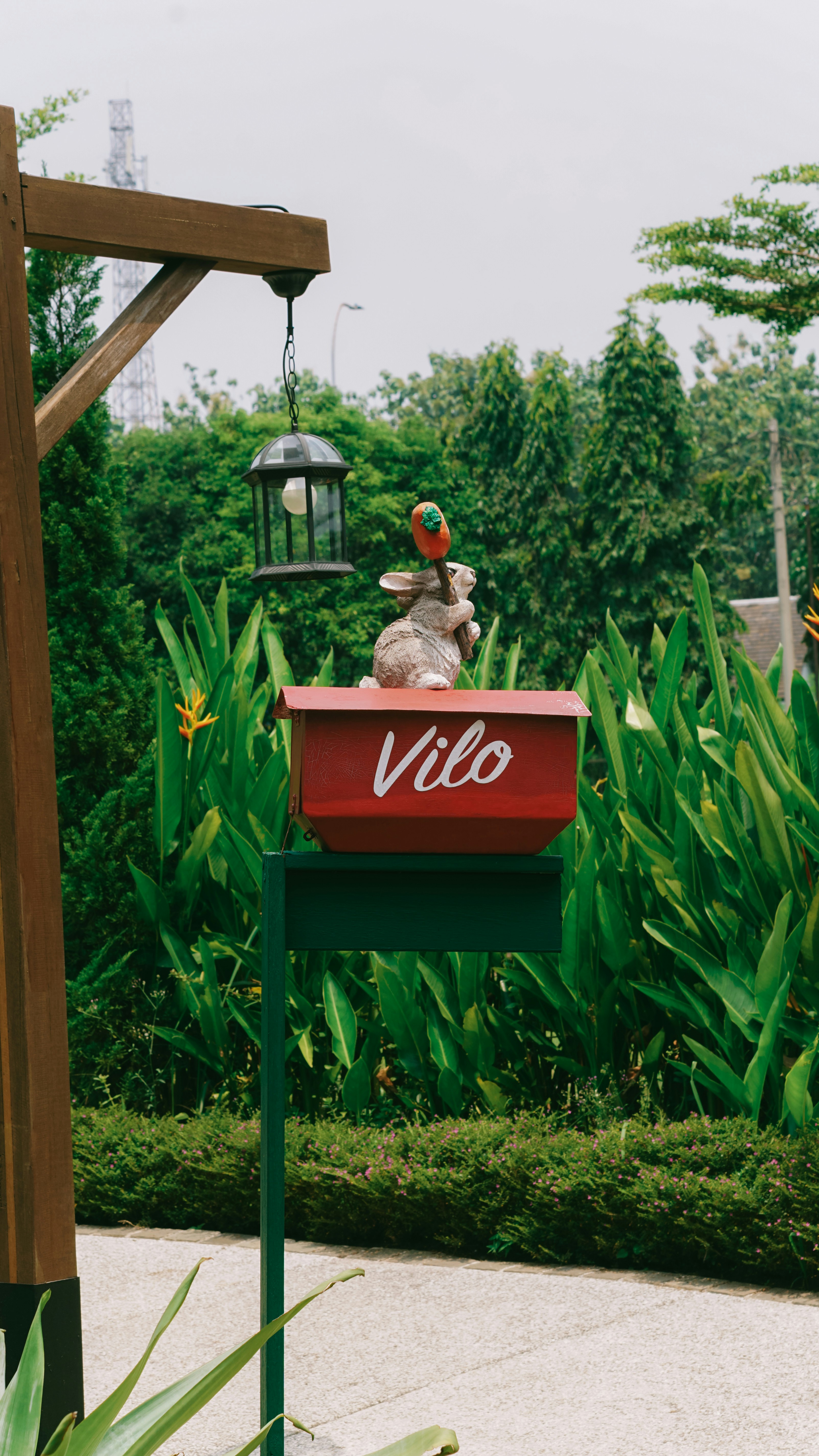 A rabbit statue sits atop a red mailbox.