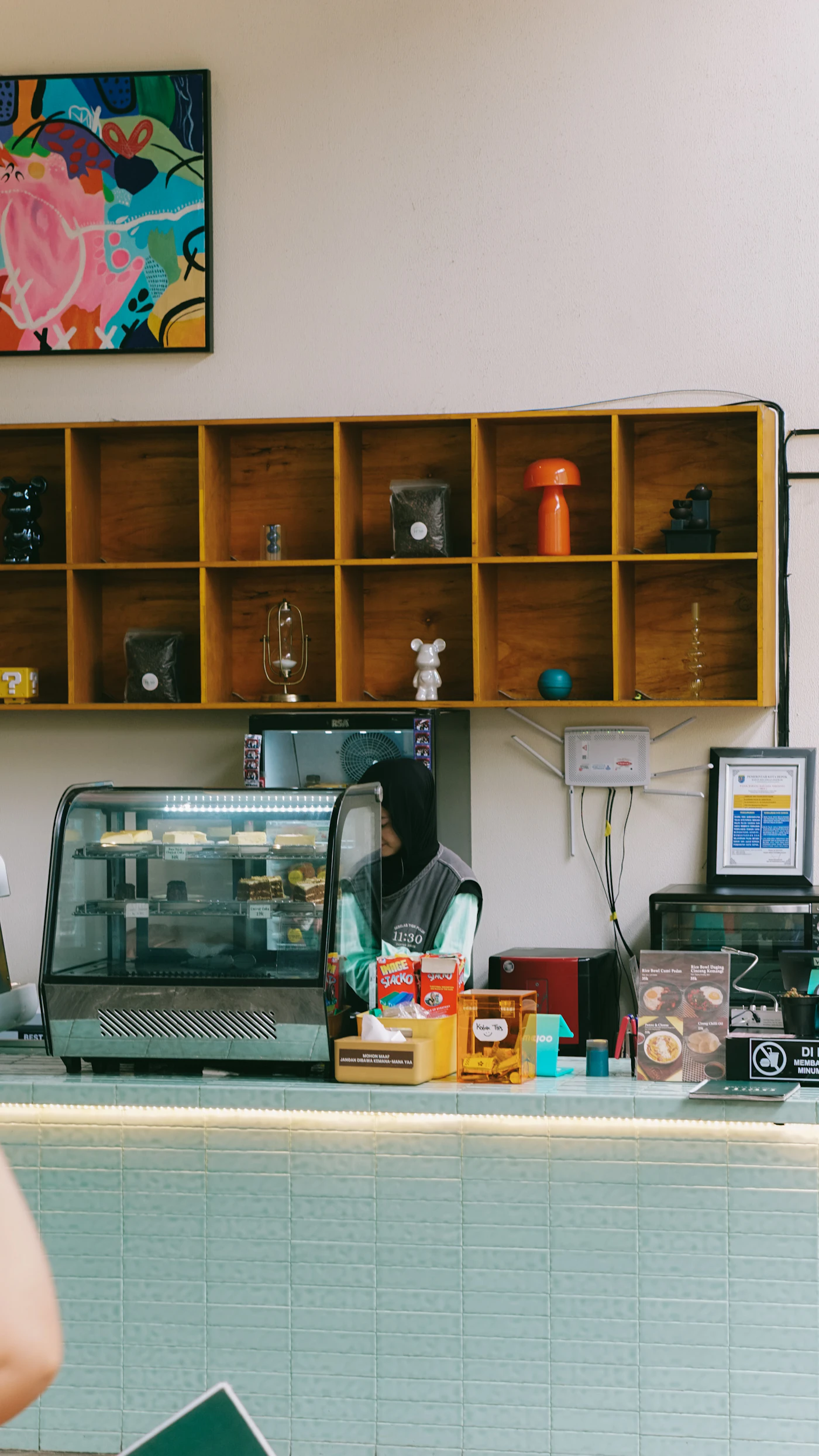 Barista detrás del mostrador con pastelería y bebidas