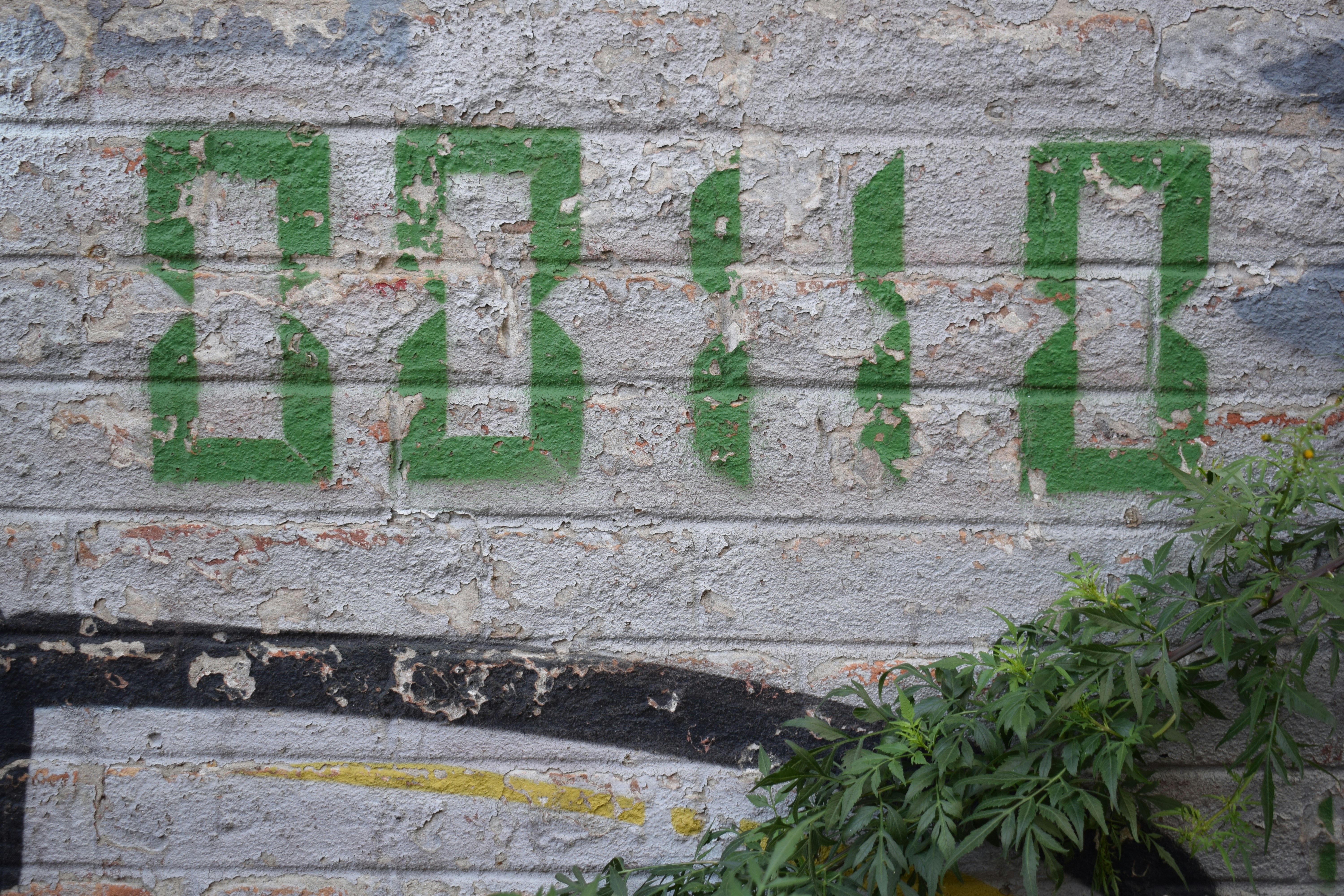 Números verdes pintados em uma parede de tijolo angustiada